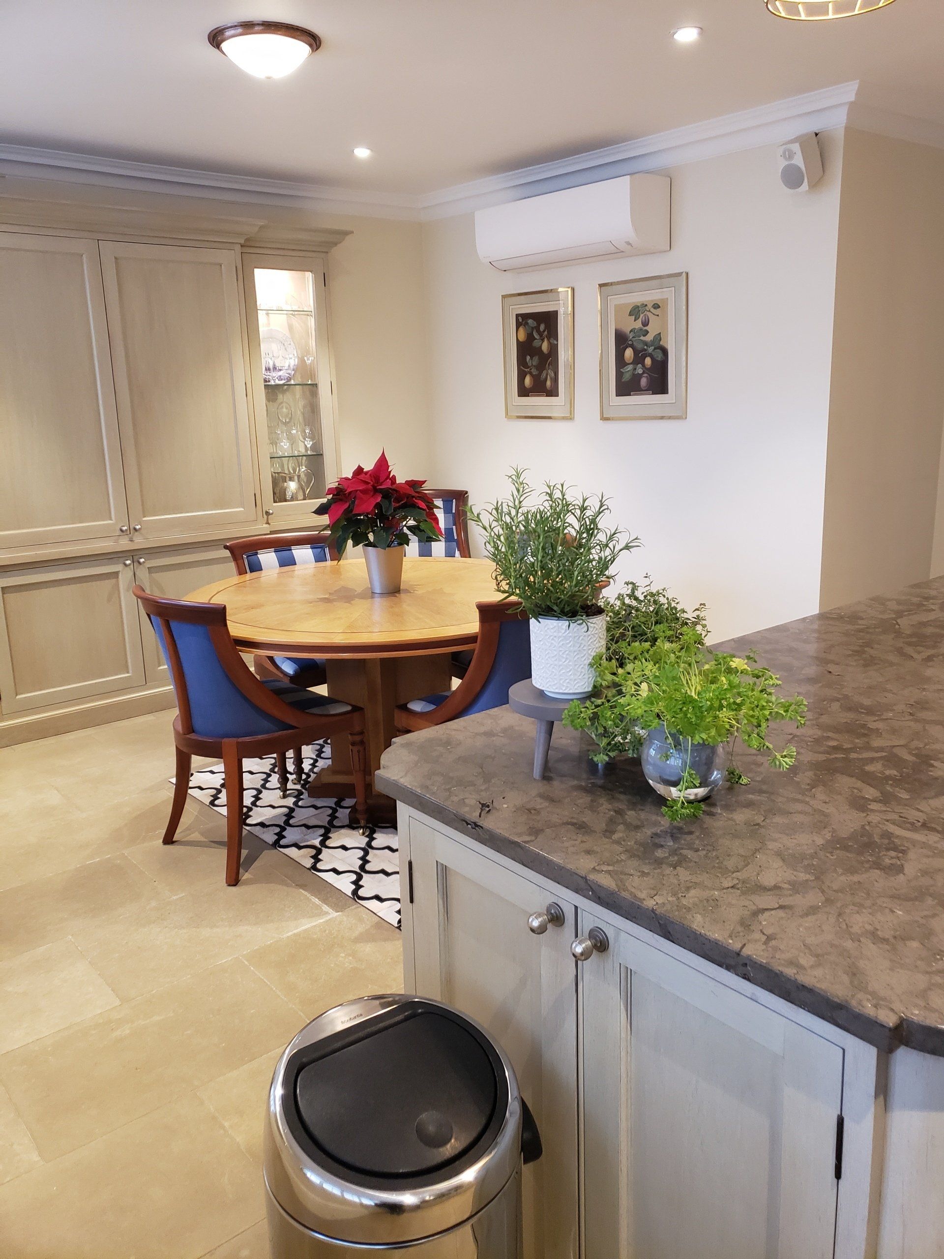 A kitchen with a table and chairs and a trash can on the counter.