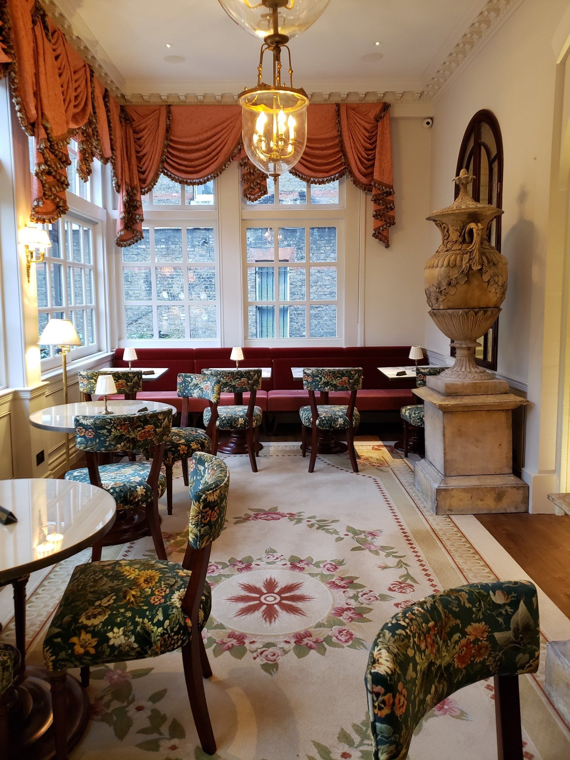 A room with tables and chairs and a vase on the wall