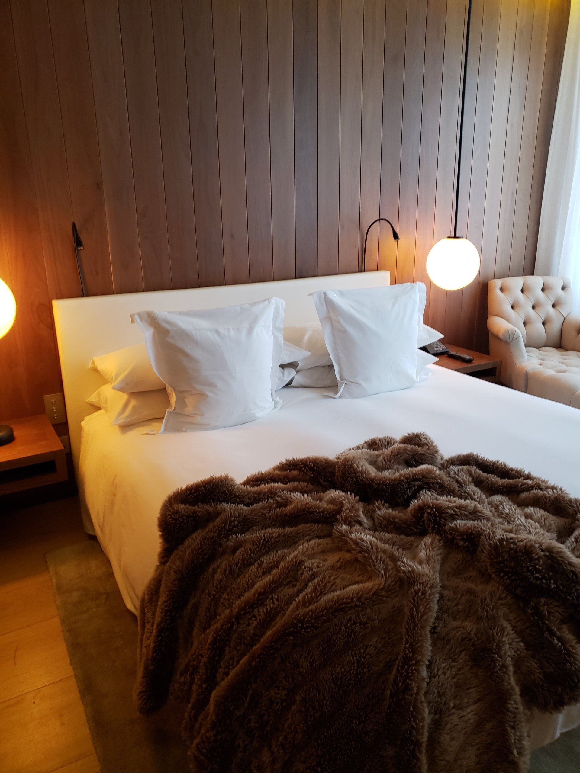 A bed with white sheets and a brown blanket on it
