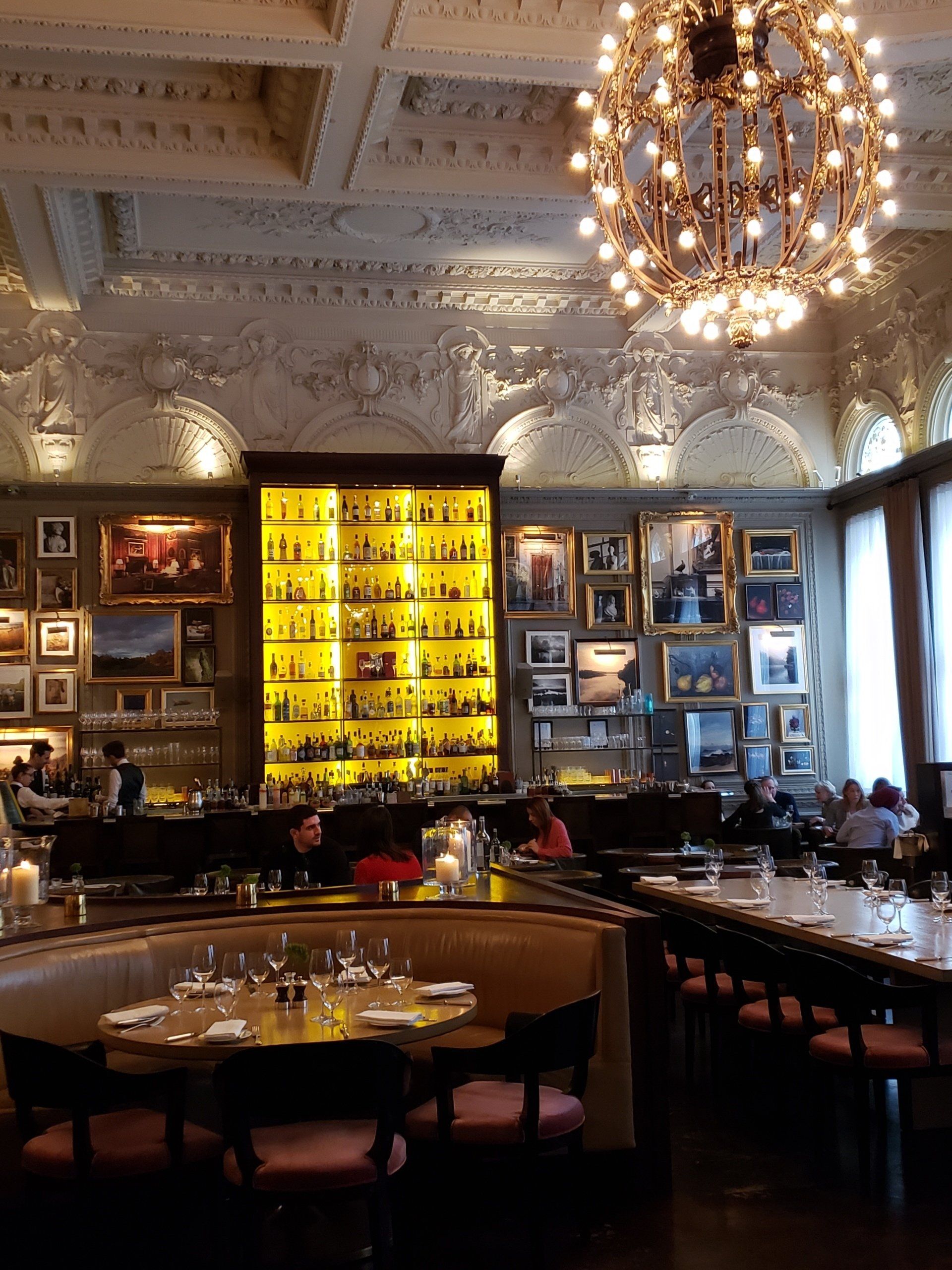 A restaurant with tables and chairs and a large chandelier