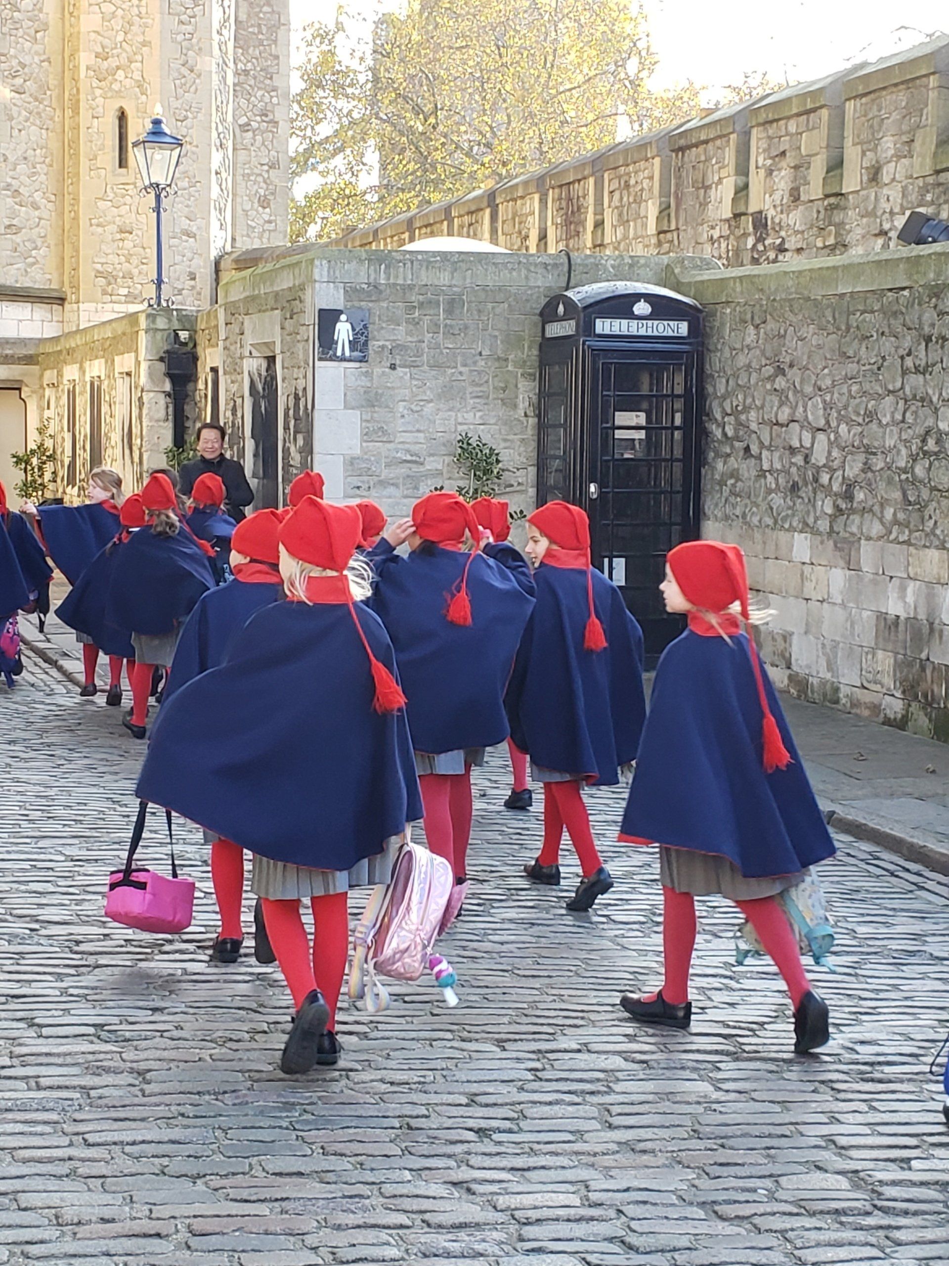 A group of children are walking down a cobblestone street.