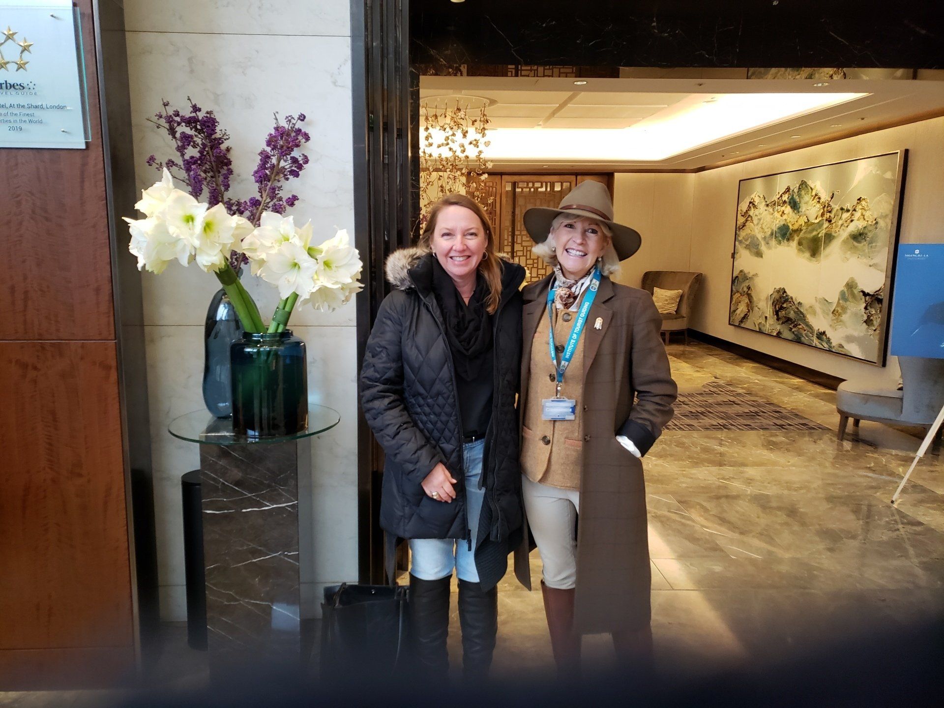 Two women are posing for a picture in a hotel lobby.