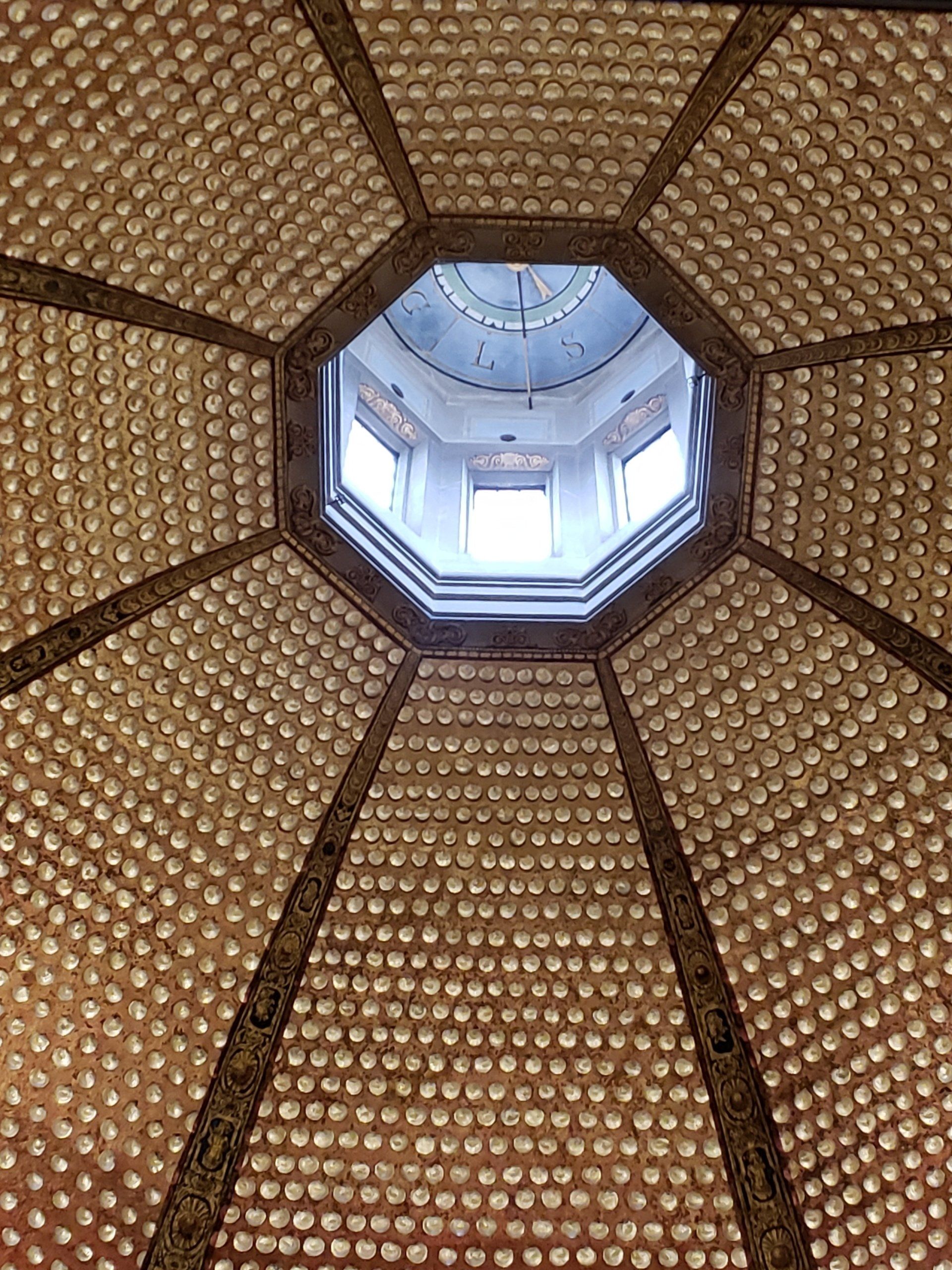 Looking up at a dome with a window in the middle.