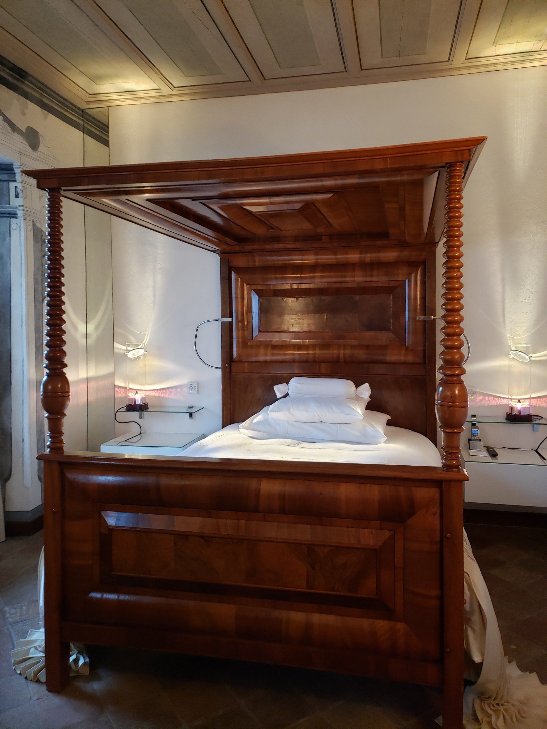 A four poster bed in a bedroom with white sheets