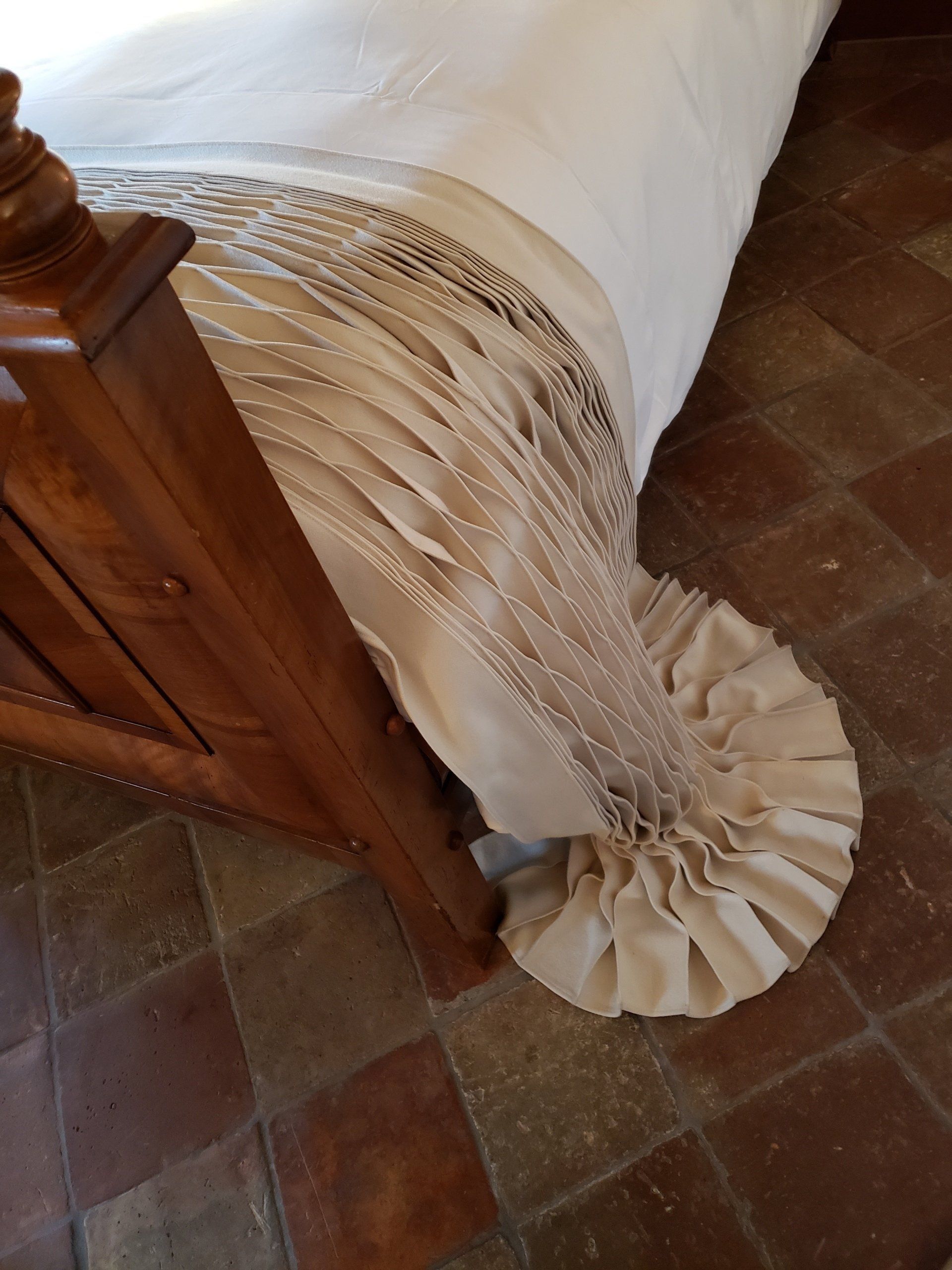 A bed with a white blanket and fringe on it