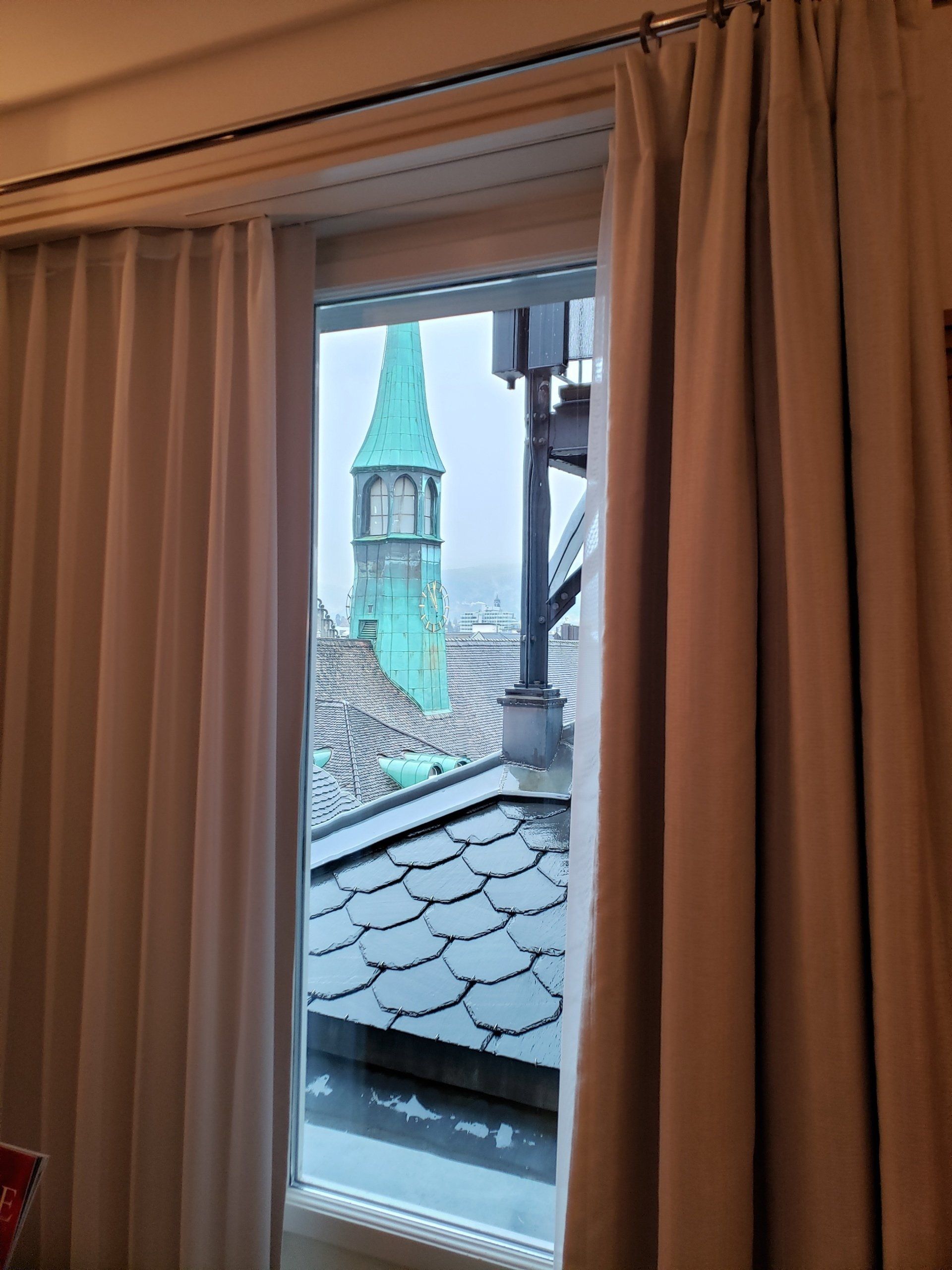 There is a view of a clock tower through a window.