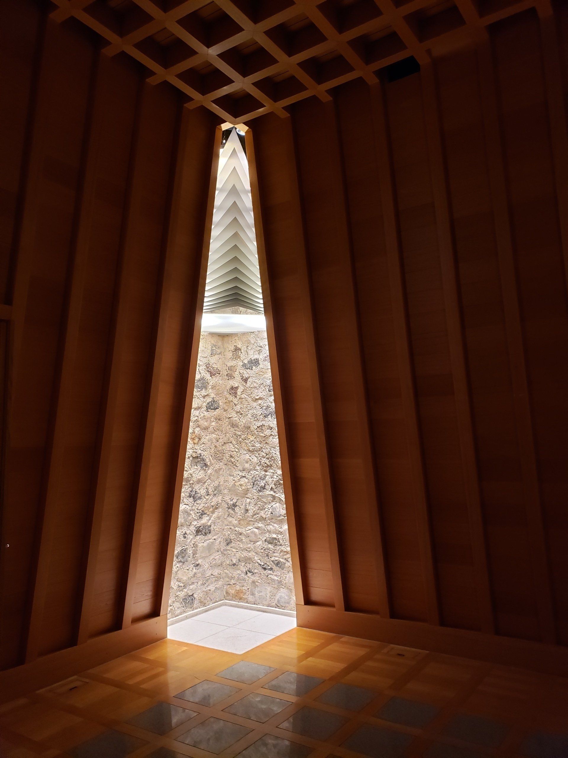 A triangle shaped window in a wooden room