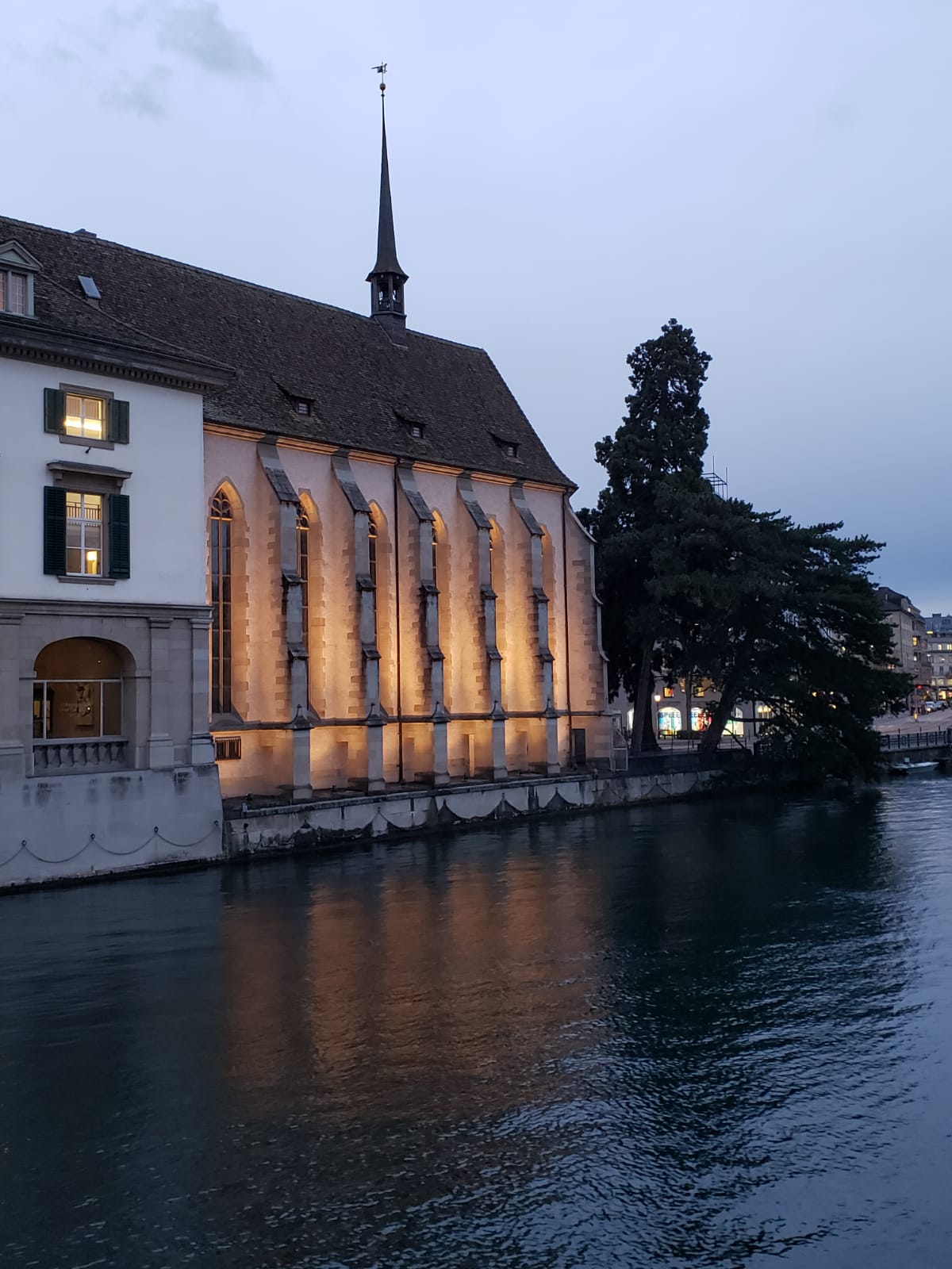 A large building is lit up next to a body of water