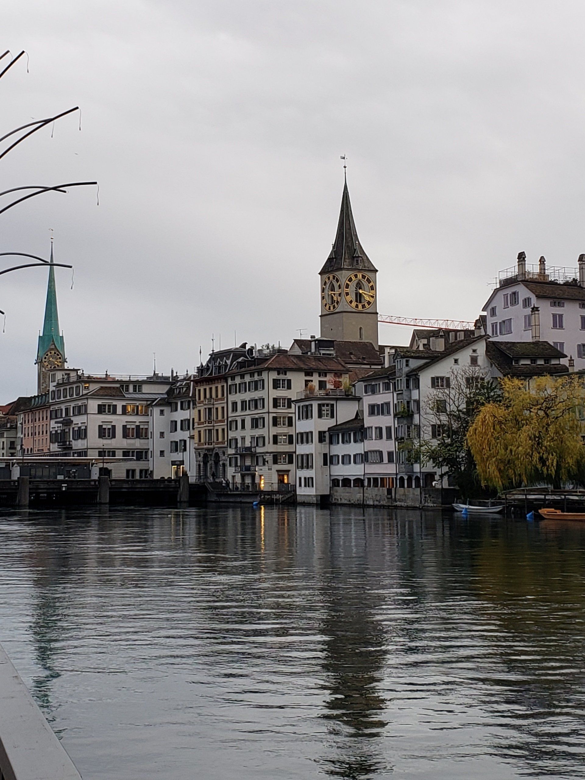 A city with a clock tower and a river in the foreground