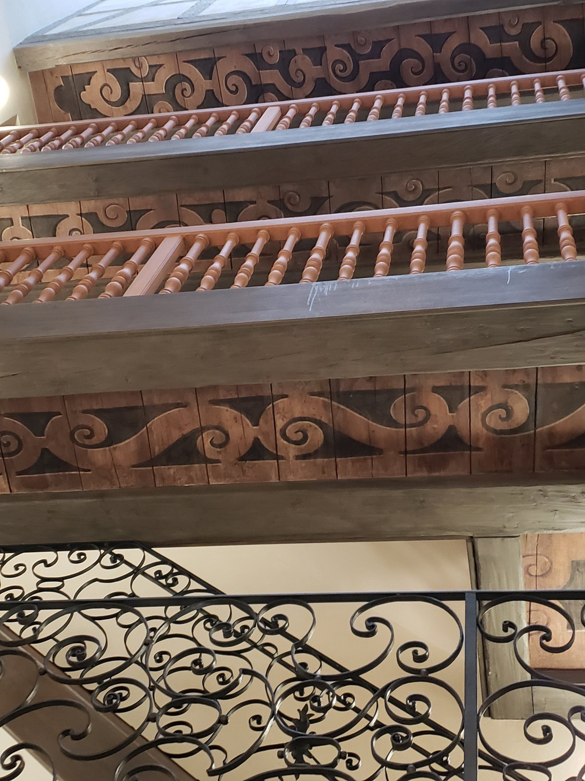 A staircase with a wooden railing and a wrought iron railing