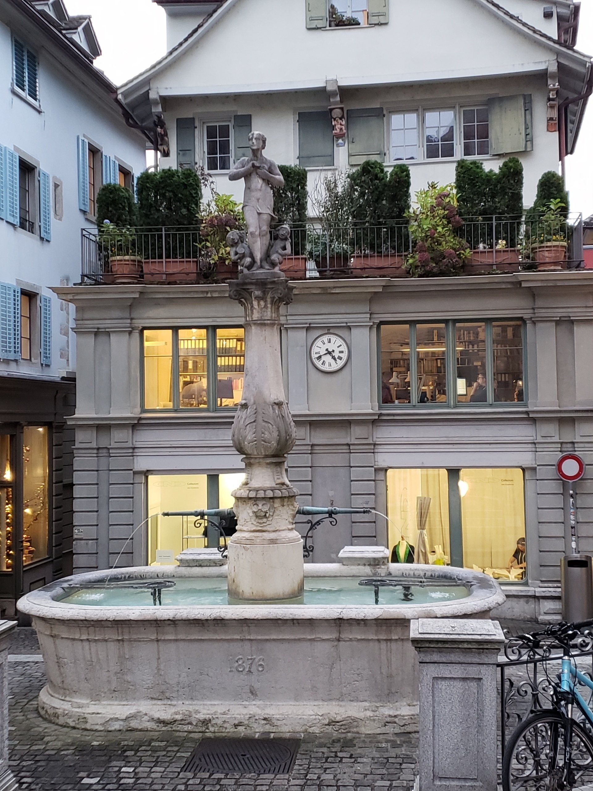 A fountain in front of a building with a clock on it