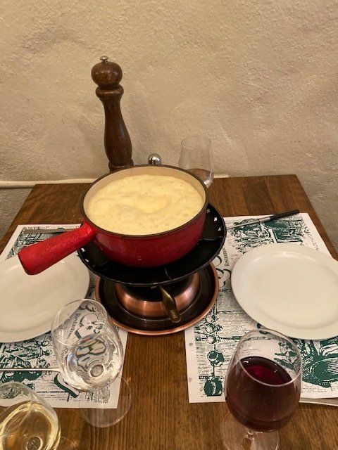 A table with a pot of fondue and a glass of wine