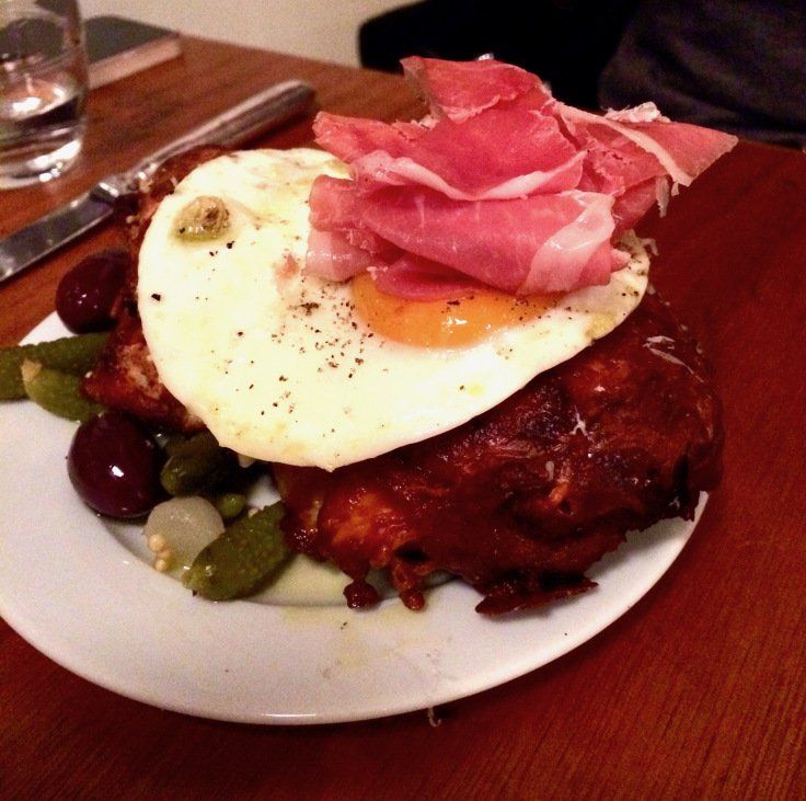 A plate of food with a fried egg and ham on top