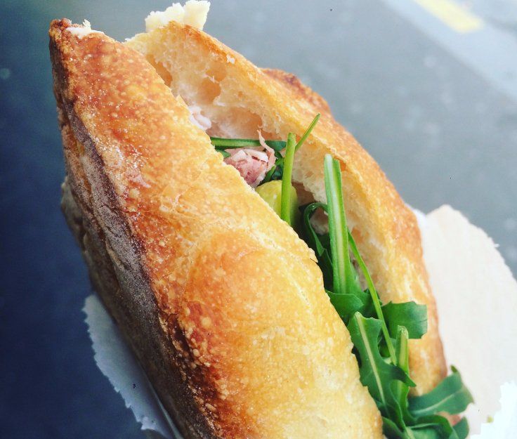 A close up of a sandwich with meat and greens
