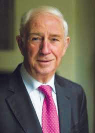 Portrait of a person wearing a dark suit, white collared shirt, and a bright pink necktie against a green background.