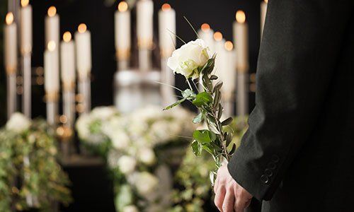 un uomo con una rosa in mano davanti e delle candele bianche accese 