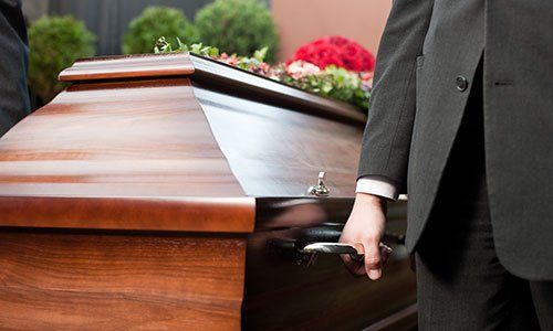 una bara con delle rose bianche sopra e accanto una