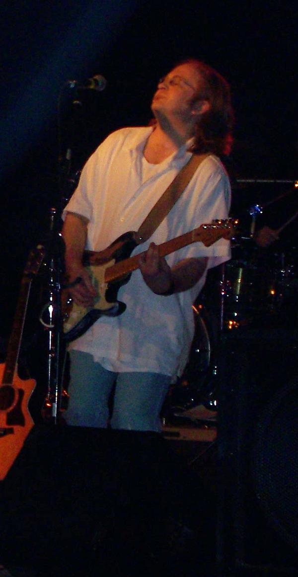 Man in white polo with red guitar