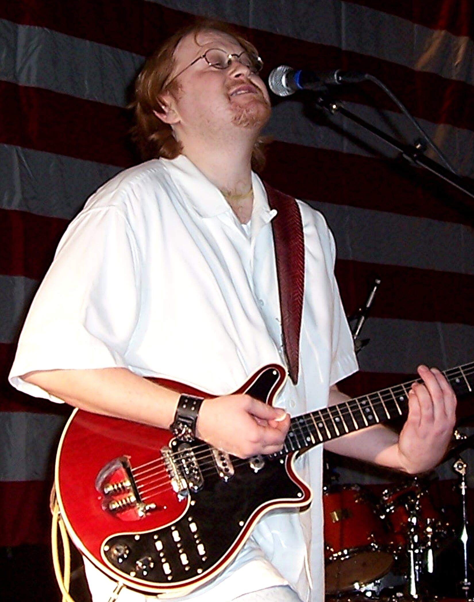 Man in white polo with red guitar