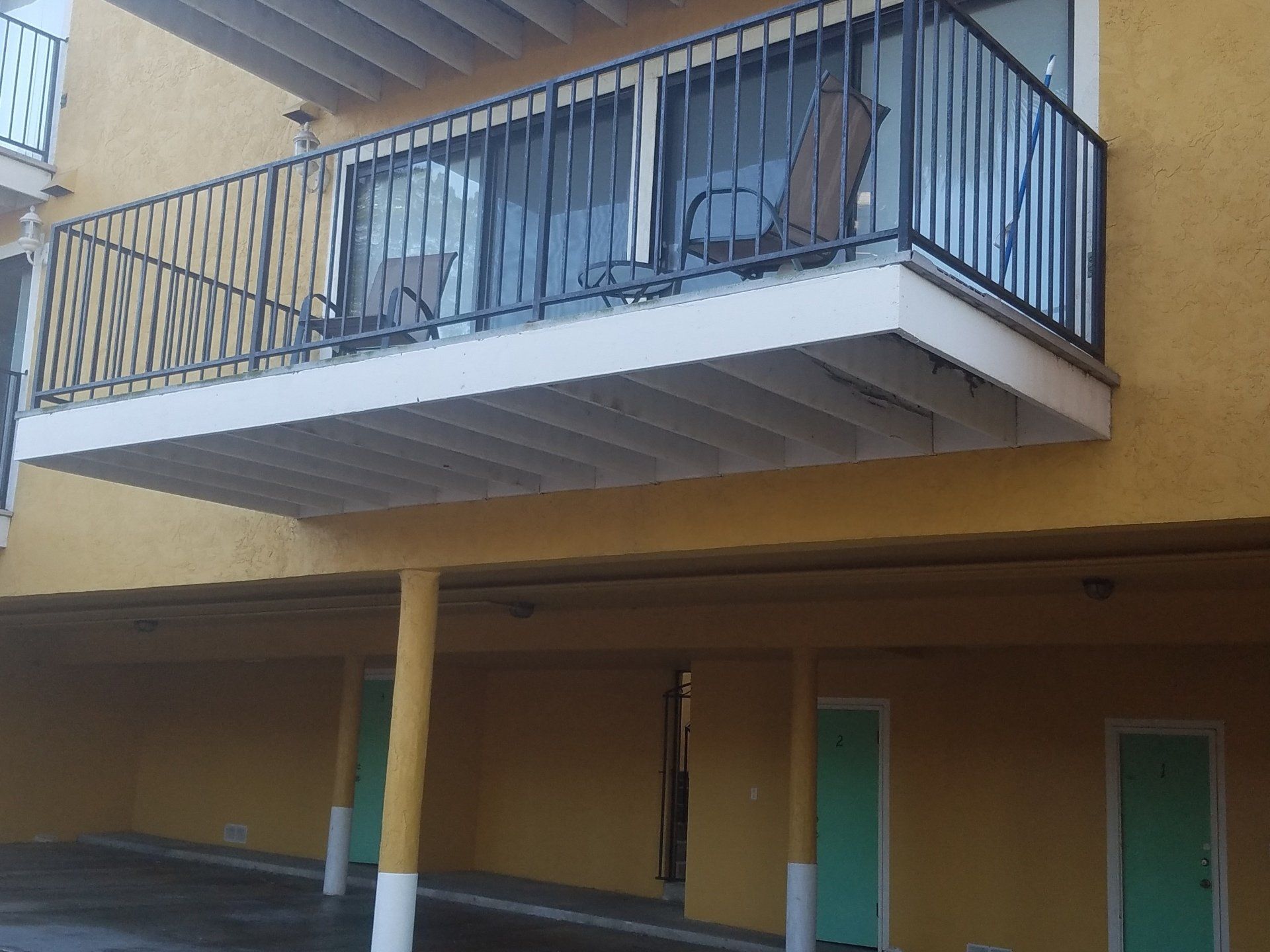 A yellow building with a balcony and green doors