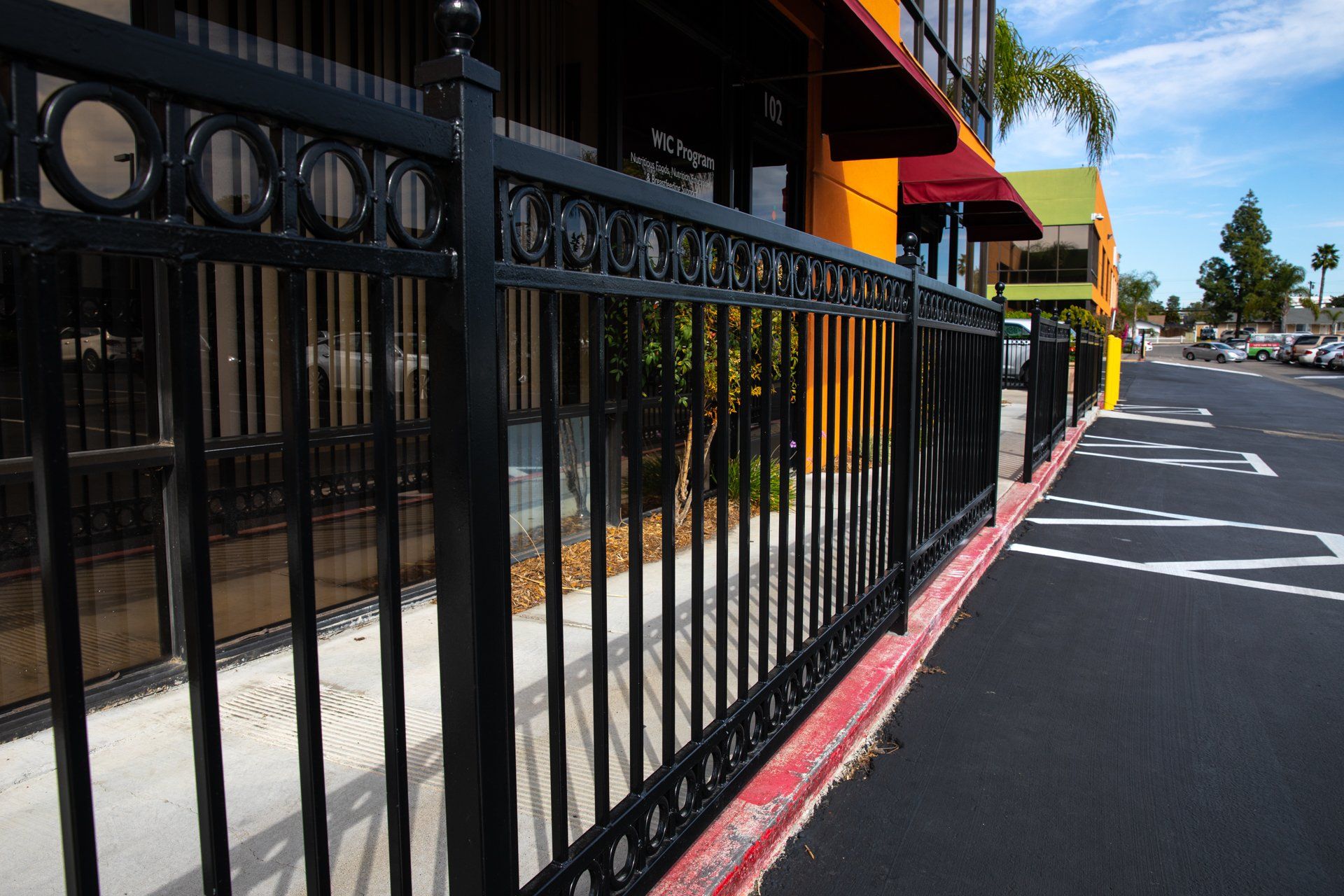 A black fence along a sidewalk in front of a building