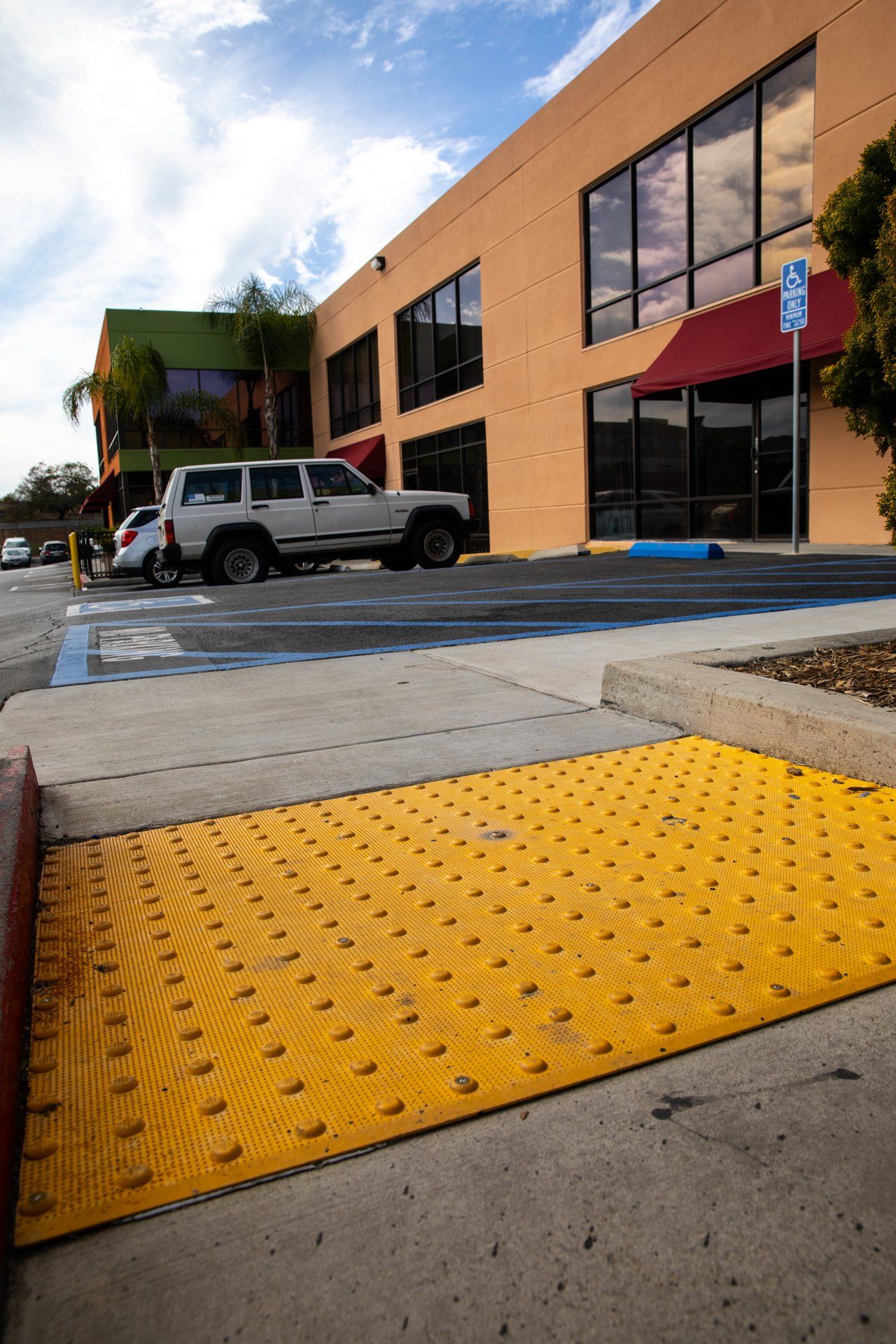 A white suv is parked in a handicapped parking spot in front of a building.