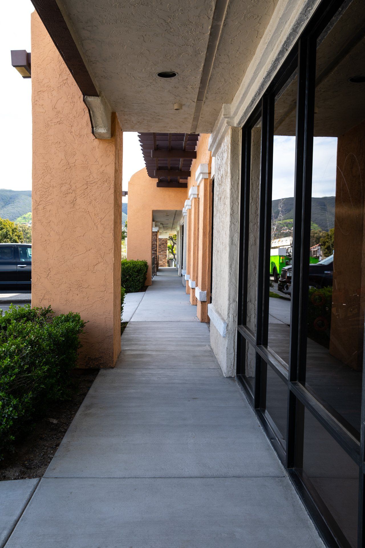 A walkway between two buildings with a car parked in the background