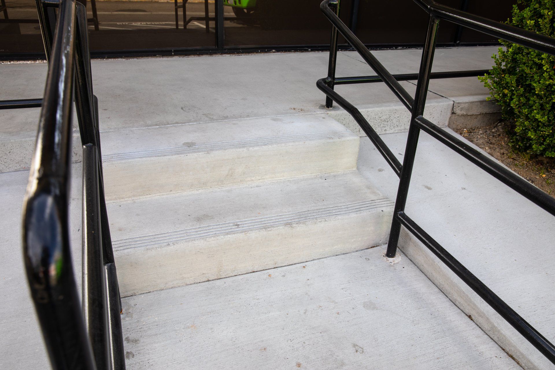A set of concrete stairs with a black railing