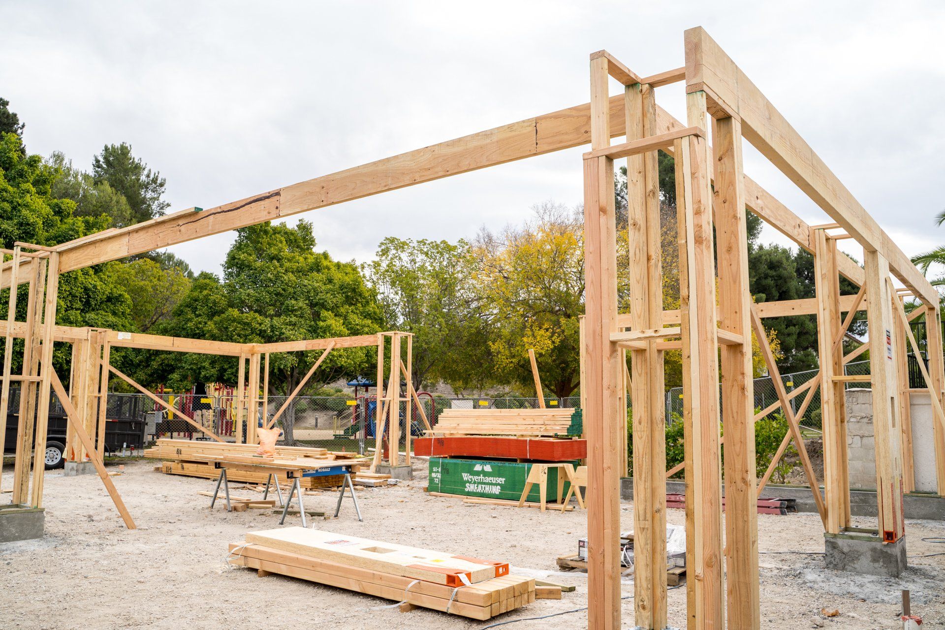 A wooden structure is being built on a dirt field.