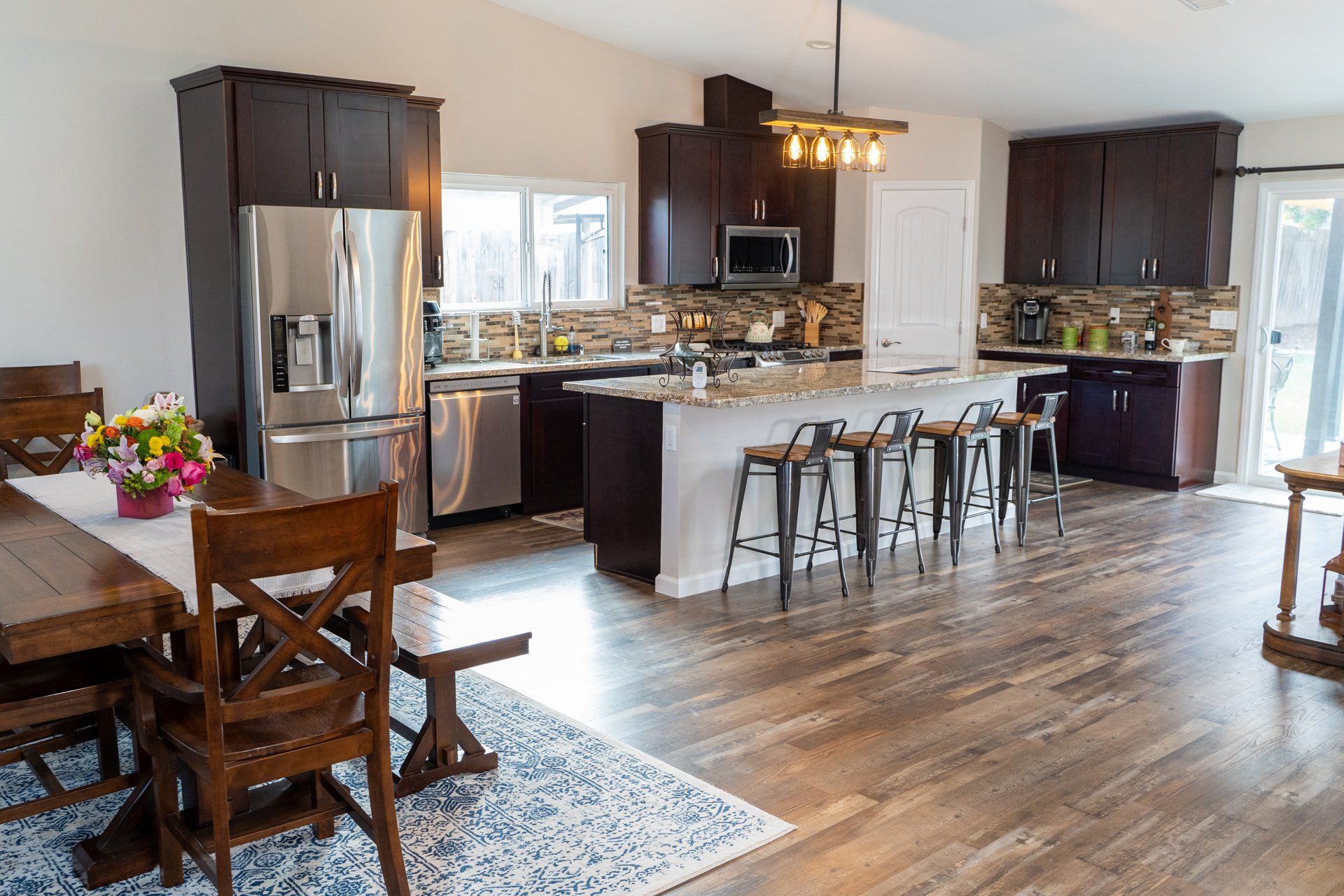 A kitchen and dining room in a house with hardwood floors and stainless steel appliances.