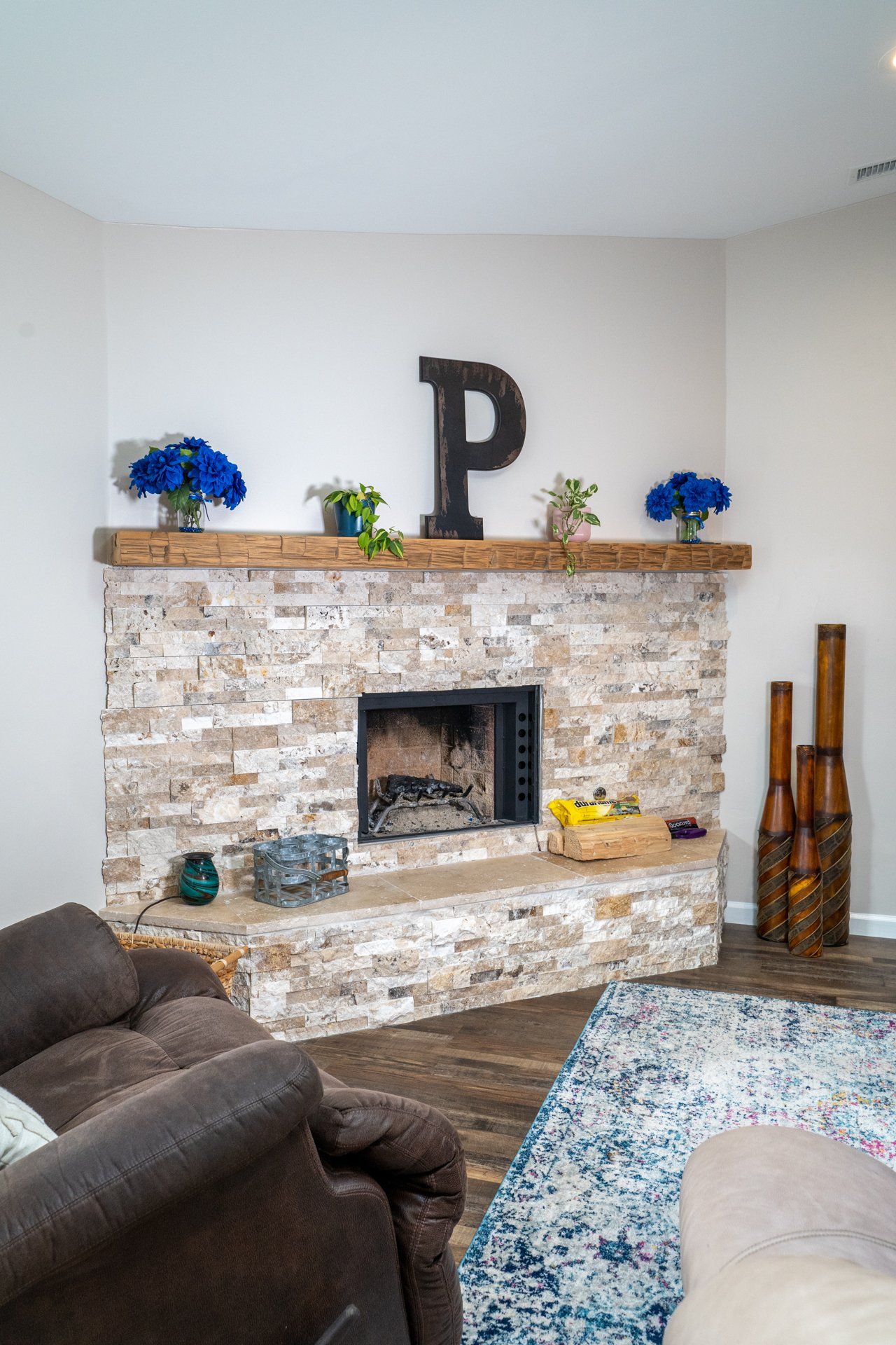 A living room with a stone fireplace and a large letter p on the mantle.