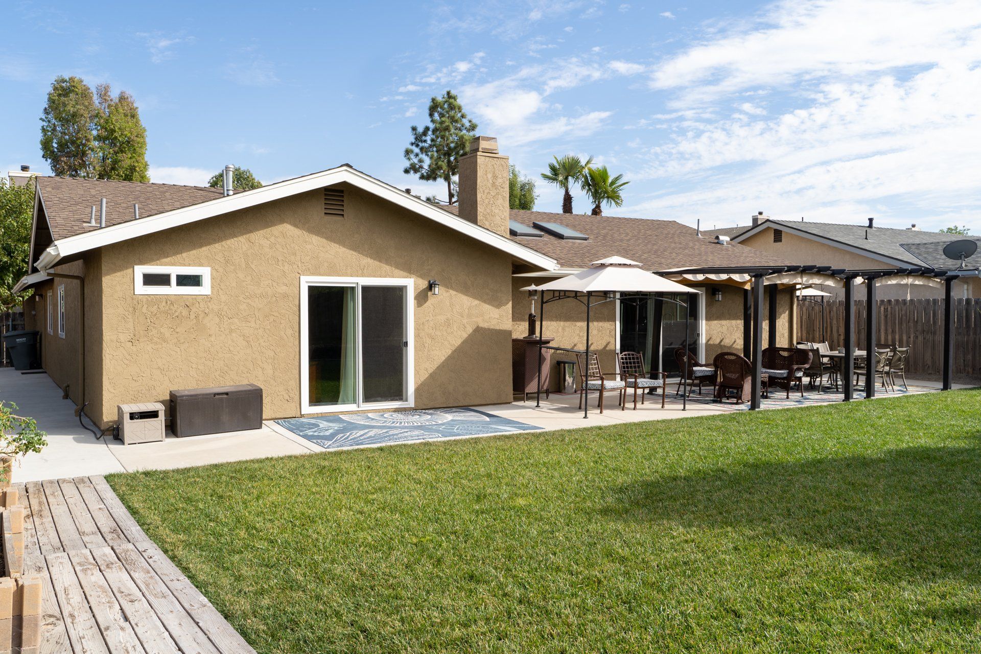 The backyard of a house with a large lawn and patio area.