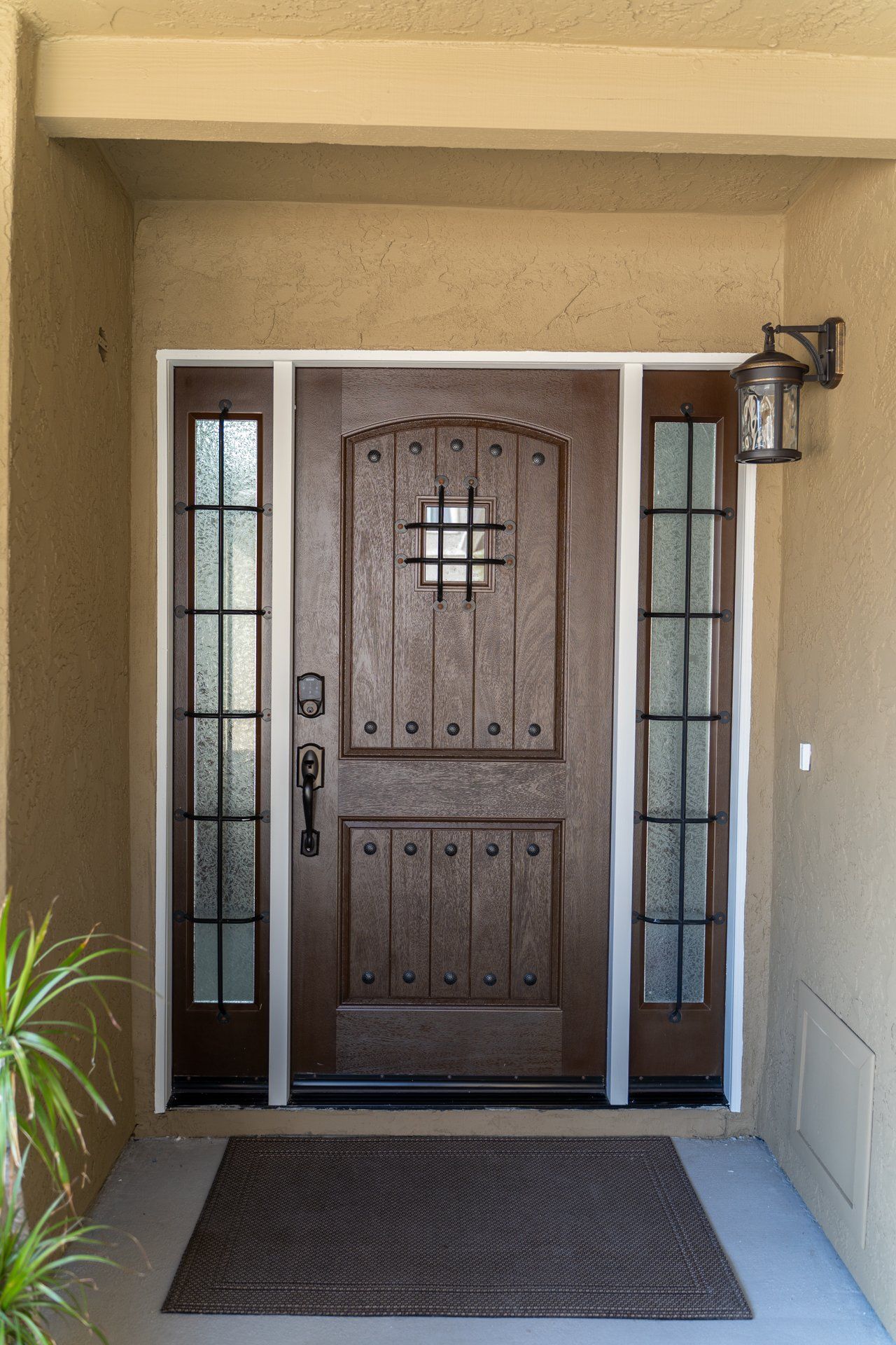 The front door of a house has a lantern on the wall above it.