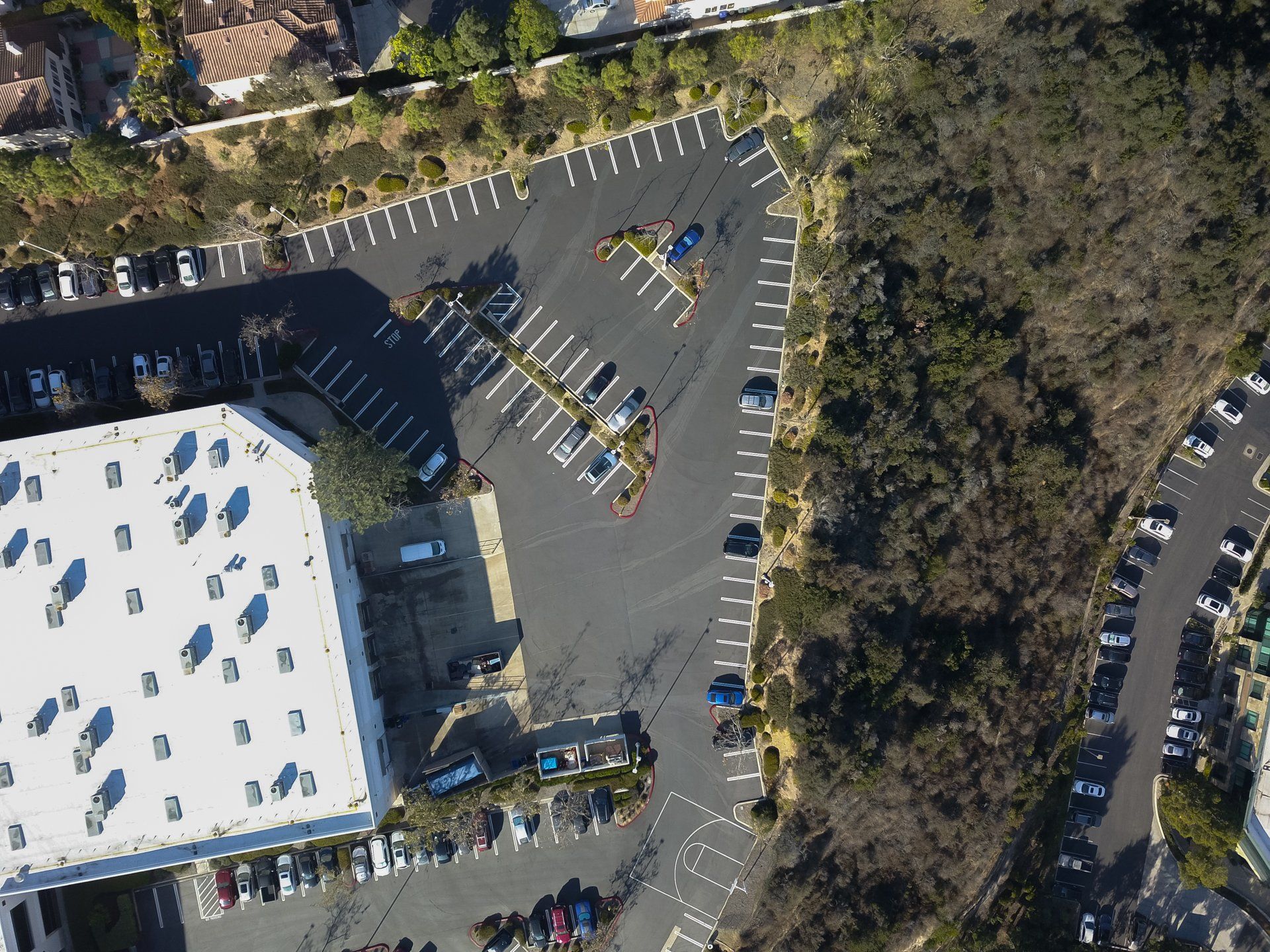 An aerial view of a parking lot with a white building in the background