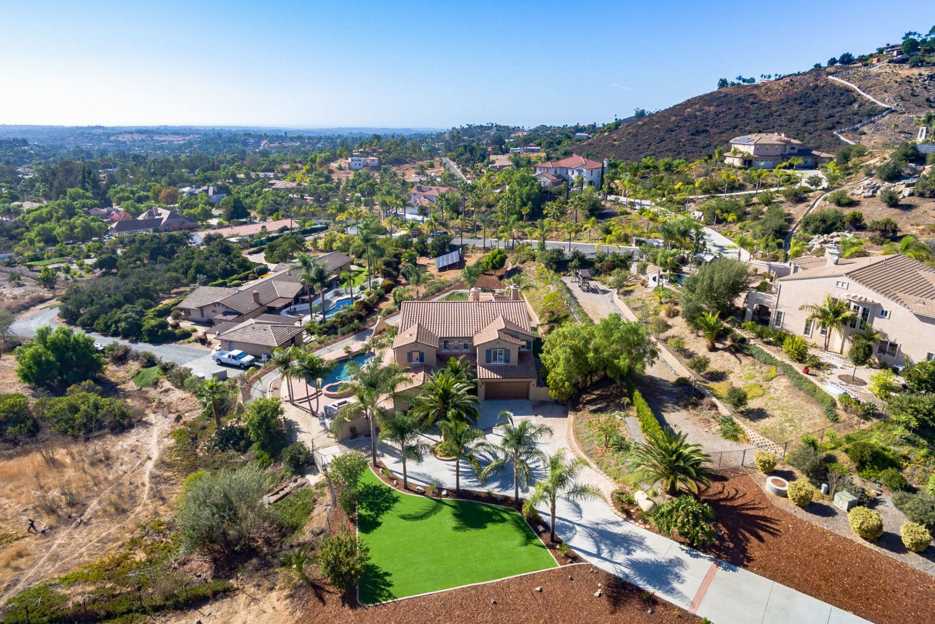 An aerial view of a house on top of a hill in a residential area.
