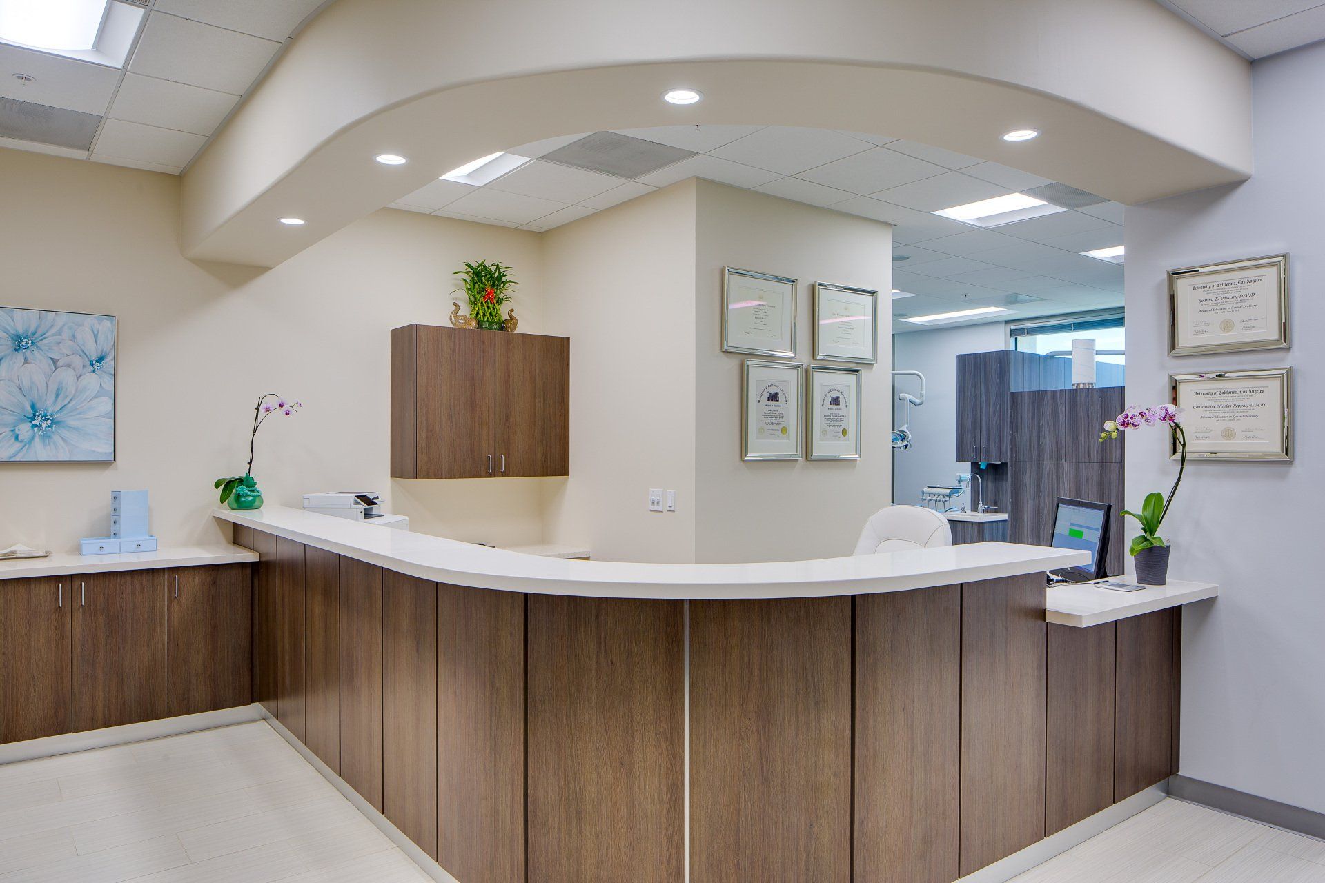 A hospital reception area with a wooden counter and a lot of certificates on the wall.
