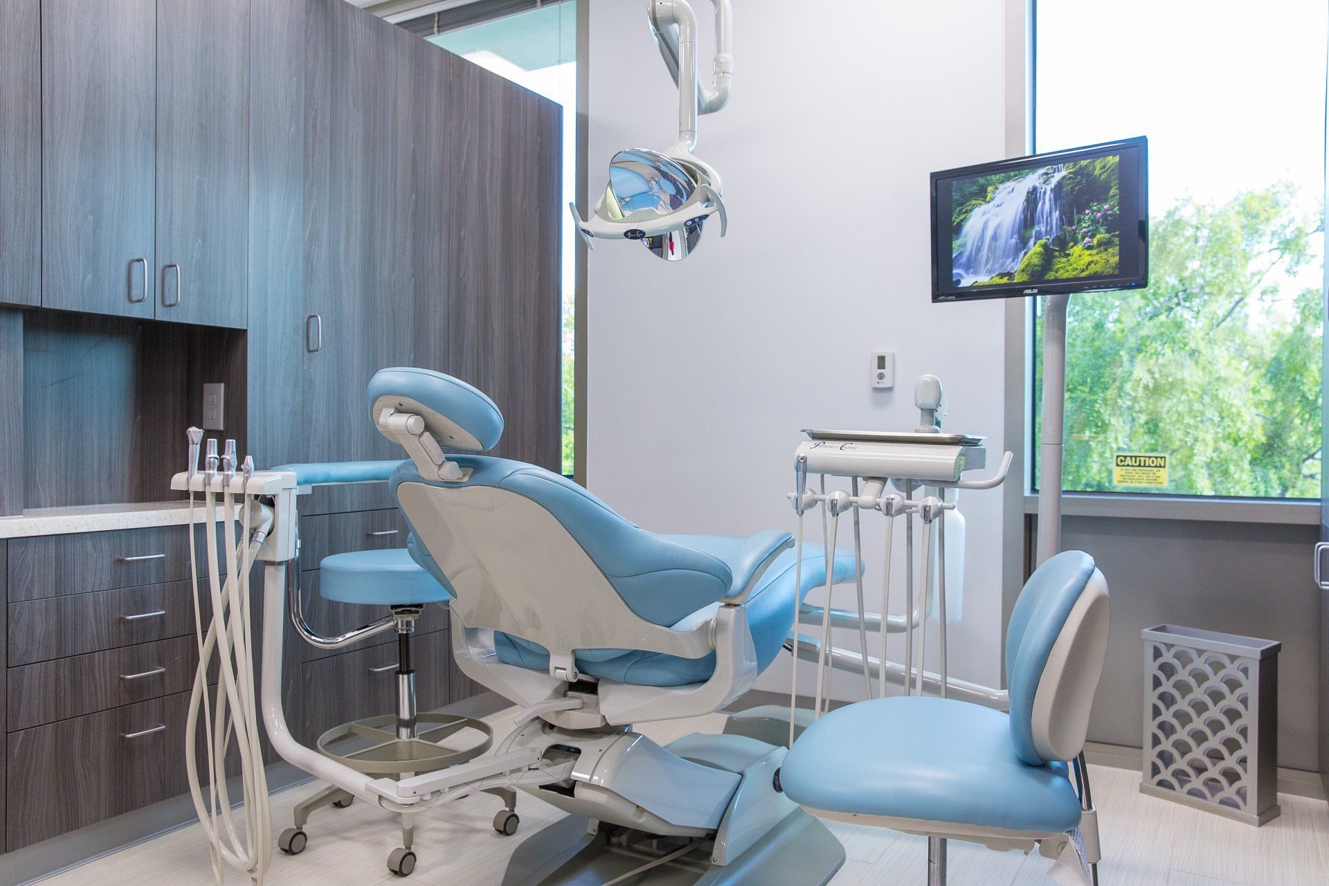 A dental office with a dental chair and a television on the wall.