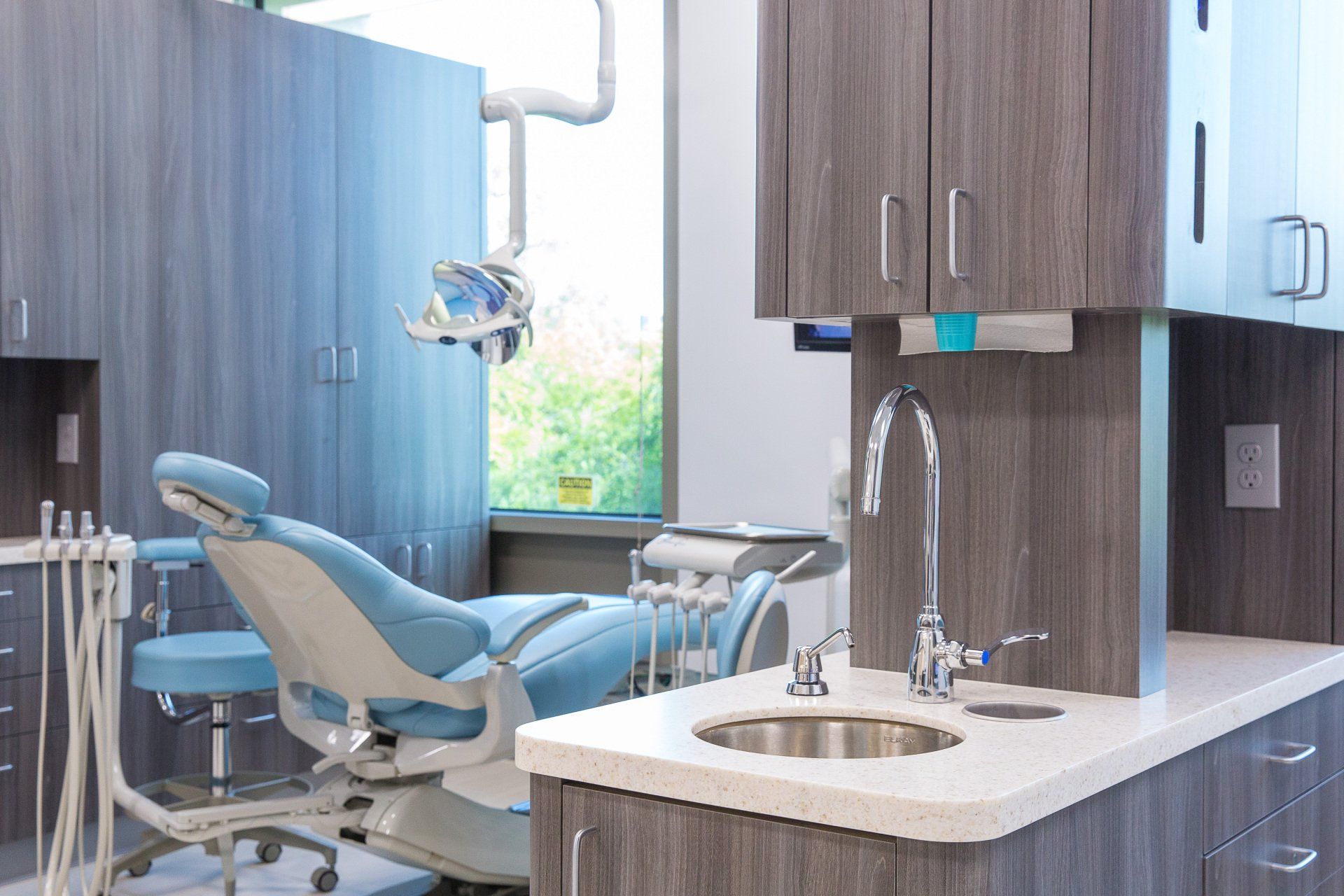 A dental office with a blue chair and a sink