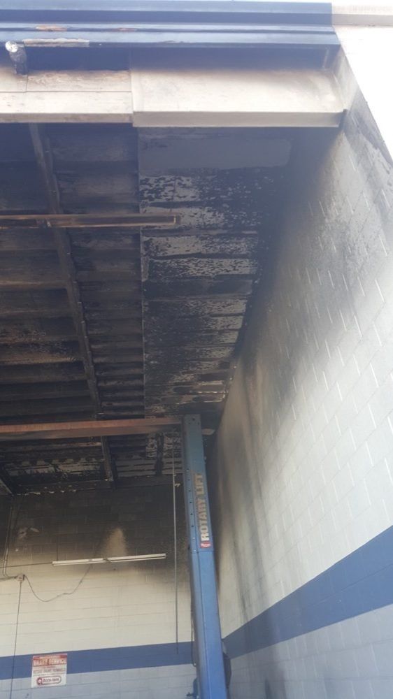 The inside of a garage with a ladder hanging from the ceiling.