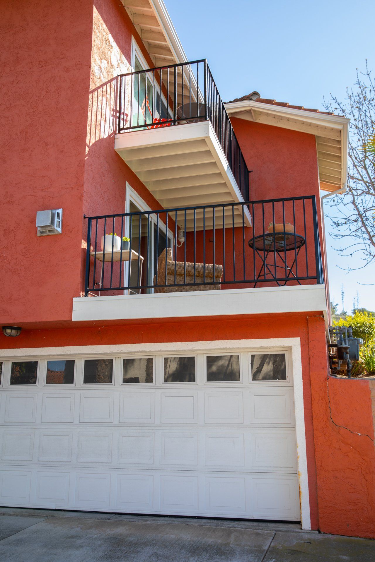 A red house with a white garage door and a balcony