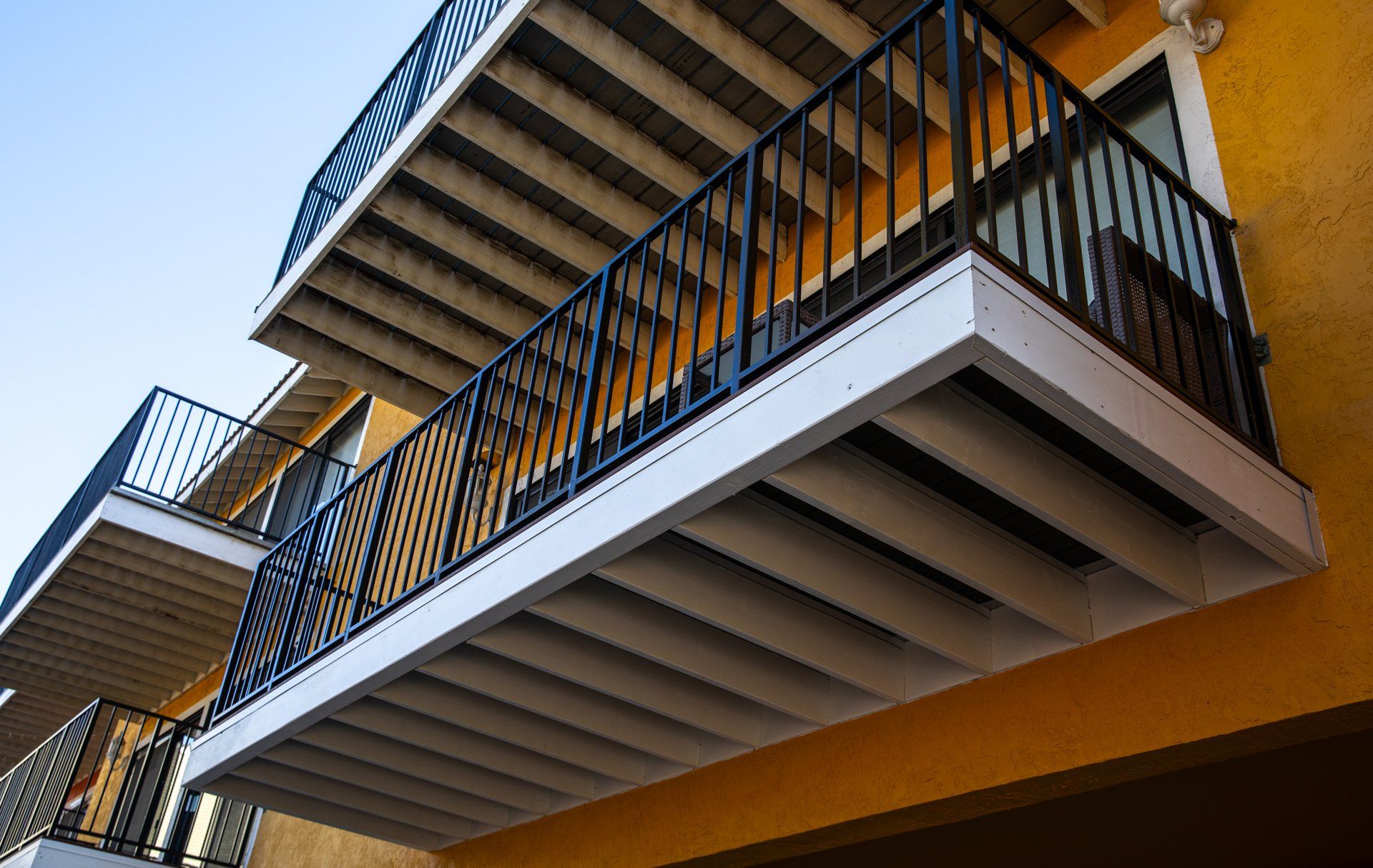 A balcony on the side of a yellow building