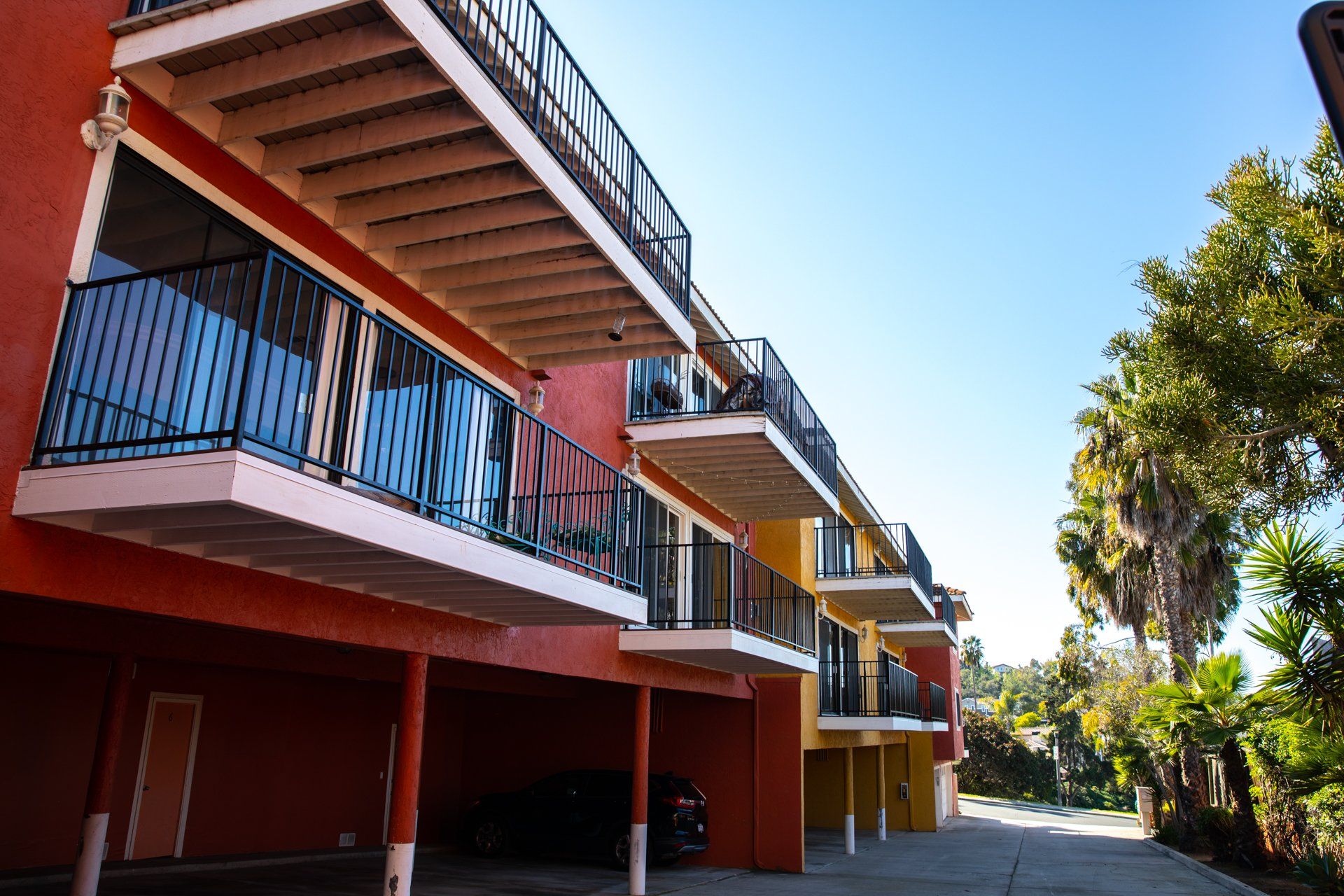 A building with balconies and a car parked underneath it