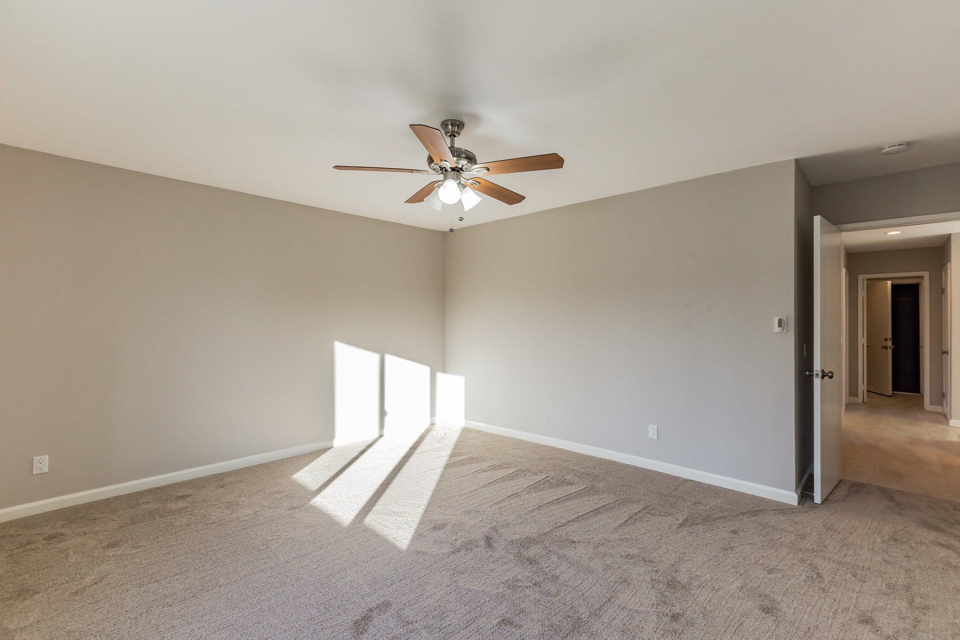 An empty bedroom with a ceiling fan and a window