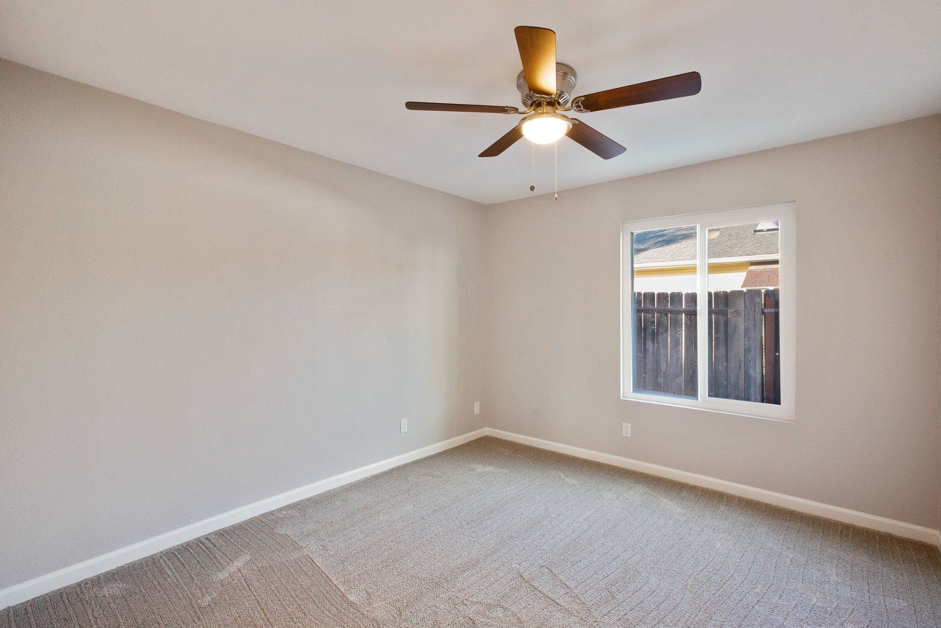 An empty room with a ceiling fan and a window