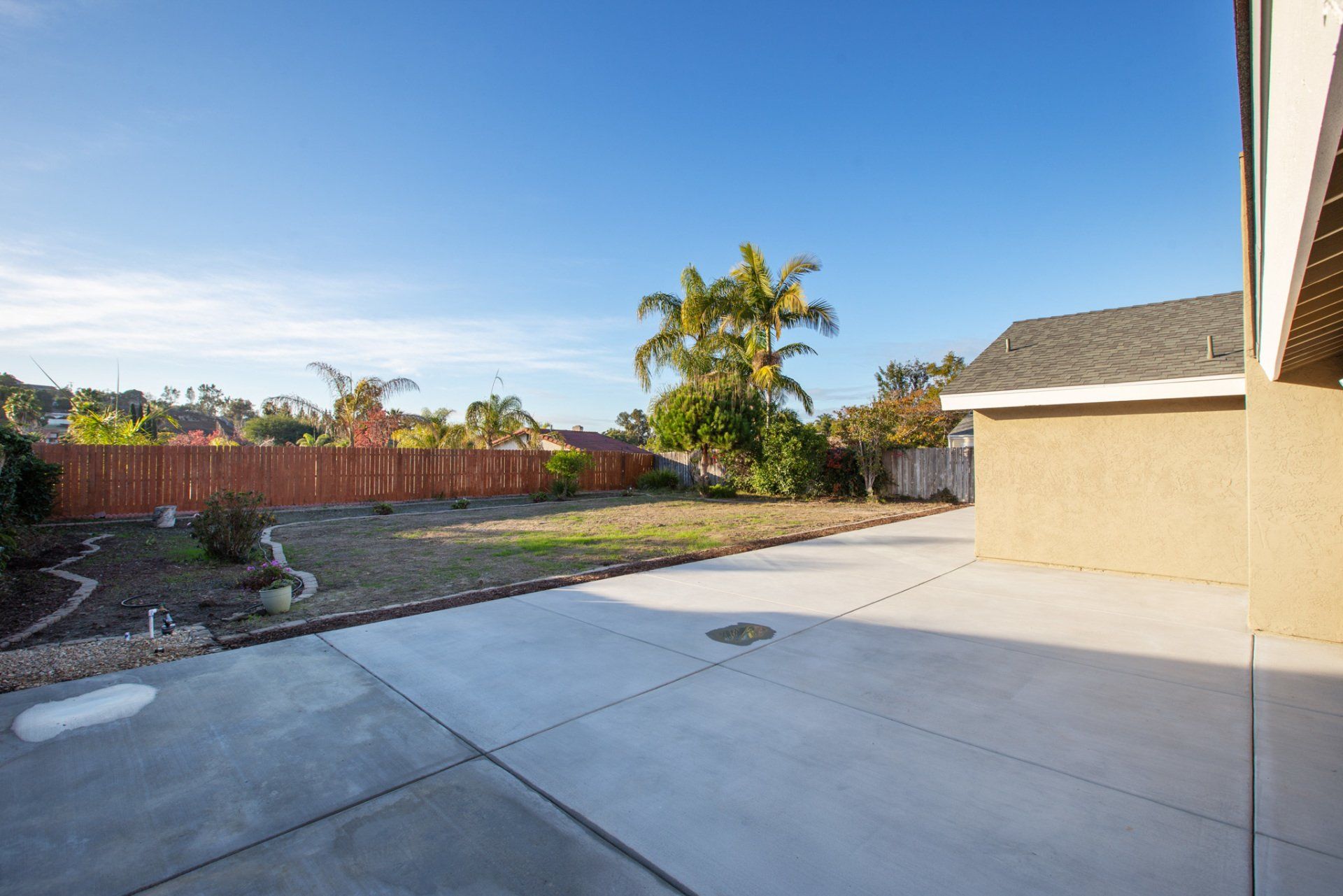 A backyard with a fence and a house in the background