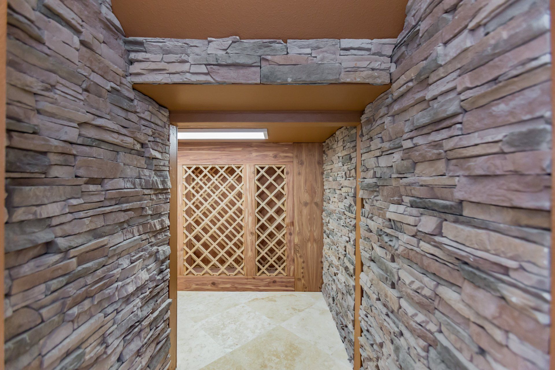A hallway with stone walls and wooden cabinets leading to a wine cellar.