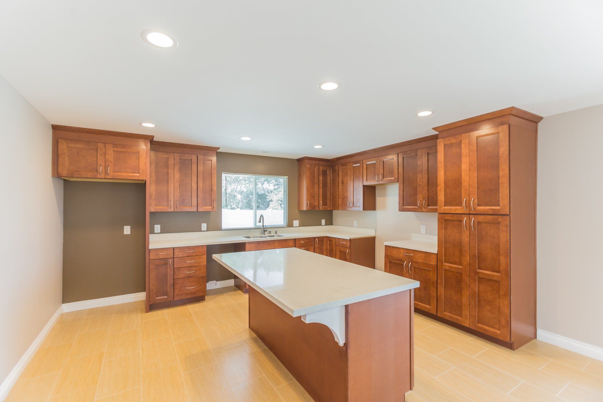 An empty kitchen with wooden cabinets and a large island