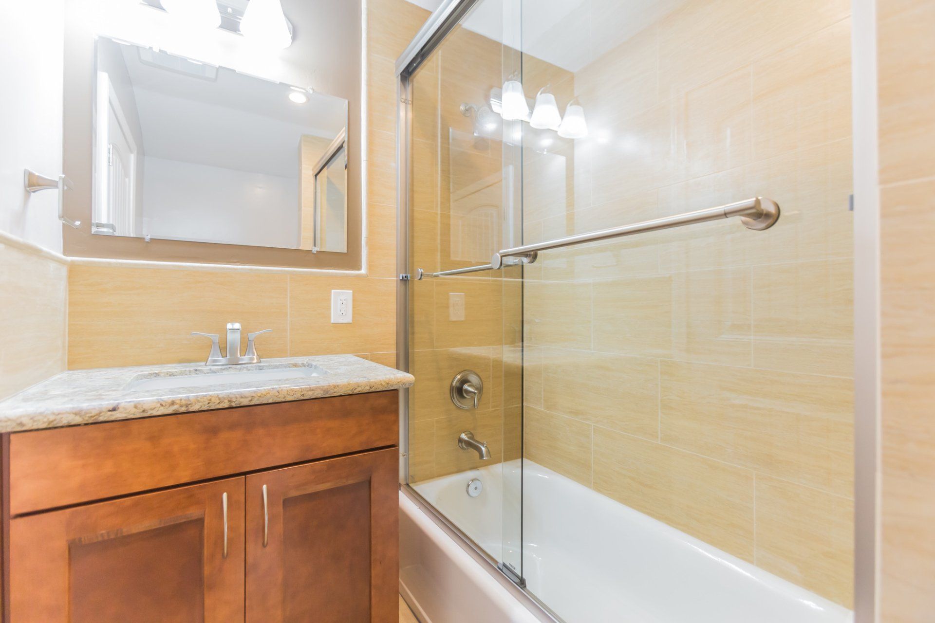 A bathroom with a sink and a bathtub with a glass shower door