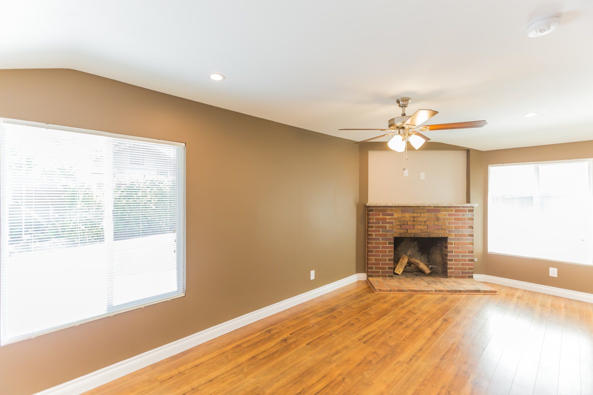 An empty living room with a fireplace and ceiling fan