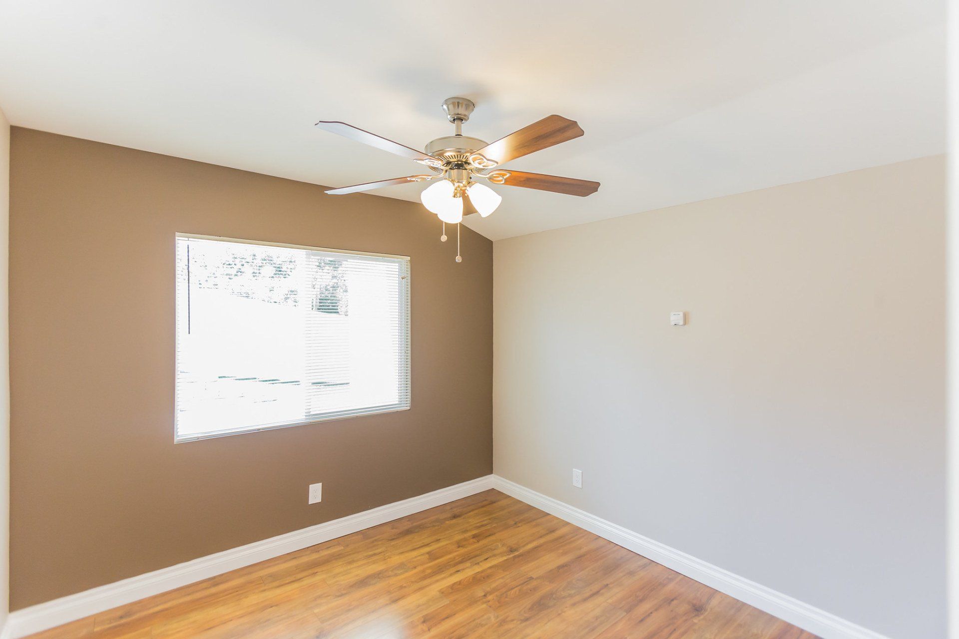 An empty room with a ceiling fan and a window